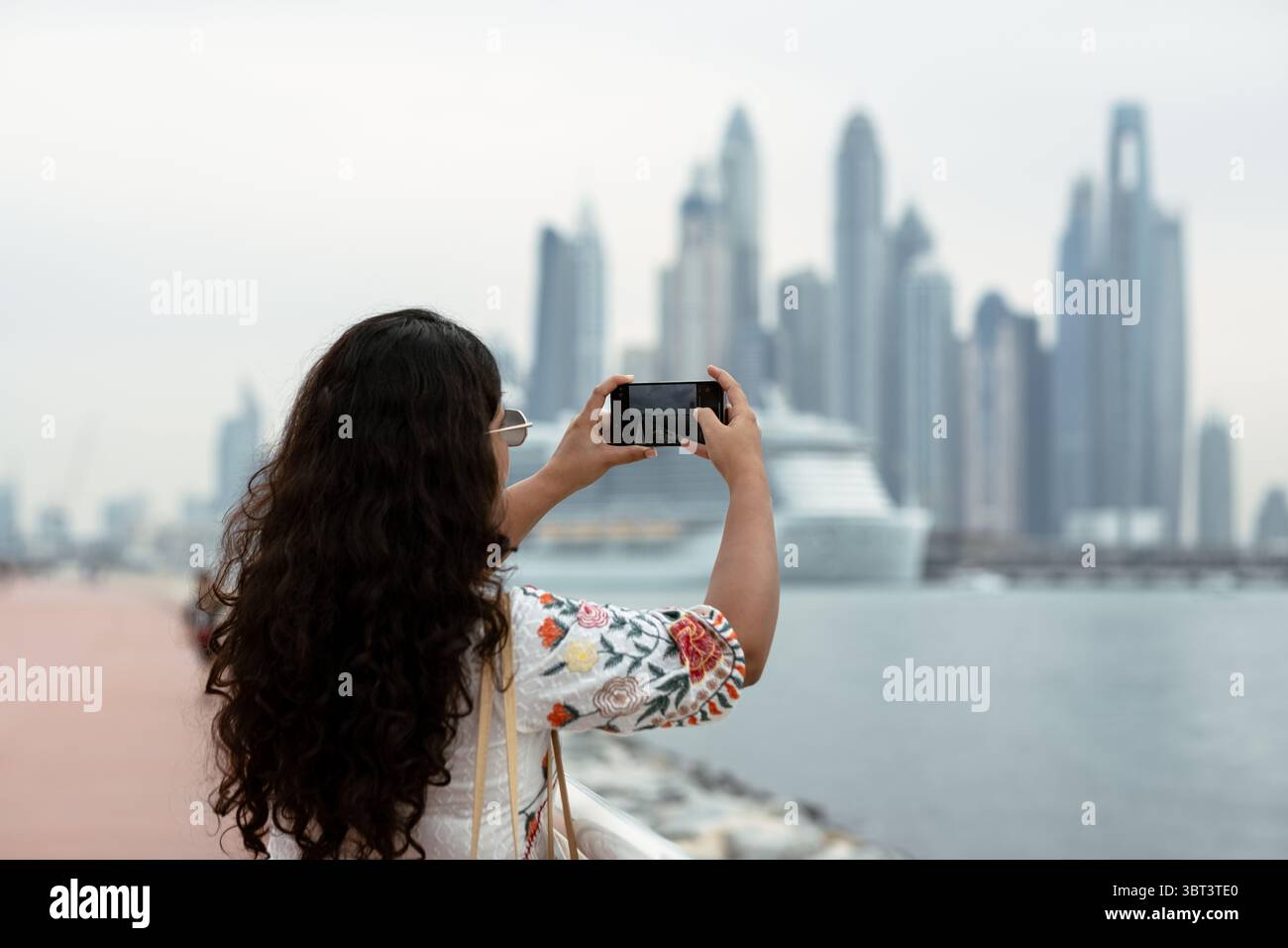 Giovane donna che esplora le viste dello skyline di Dubai Marina. Sta facendo clic sulle foto sull'isola di Palm Jumeirah Foto Stock