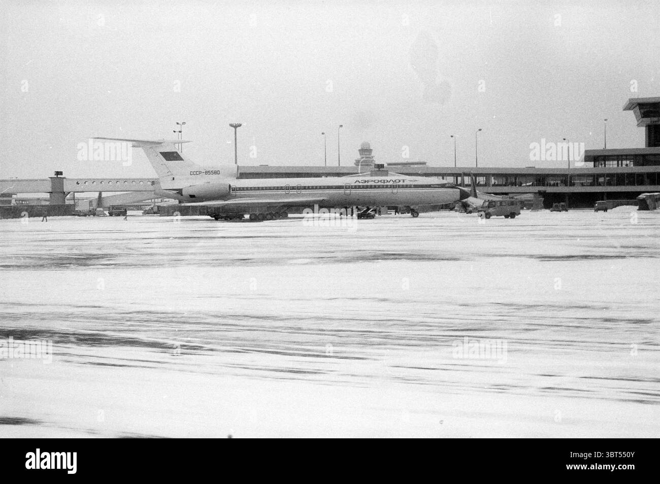 Spazzaneve Schiphol Snow Schiphol Schiphol, Whizgle News, Dutch Desk, Paesi Bassi, 1950 - 2000 il 23-01-1984. Questi sono gli argomenti nell'immagine. La scena cattura un paesaggio invernale dell'aeroporto sotto cieli ricoperti, dove l'atmosfera sembra fredda e soffusa. Un grande aereo, caratterizzato dalla fusoliera allungata e da una caratteristica pinna di coda, occupa il primo piano, stazionario su una pista coperta da una fitta coperta di neve bianca. Il suo corpo è dipinto in una tavolozza sfumata, principalmente bianca con accenti blu scuro, che accentuano il netto contrasto con lo sfondo invernale. Dintorni Foto Stock