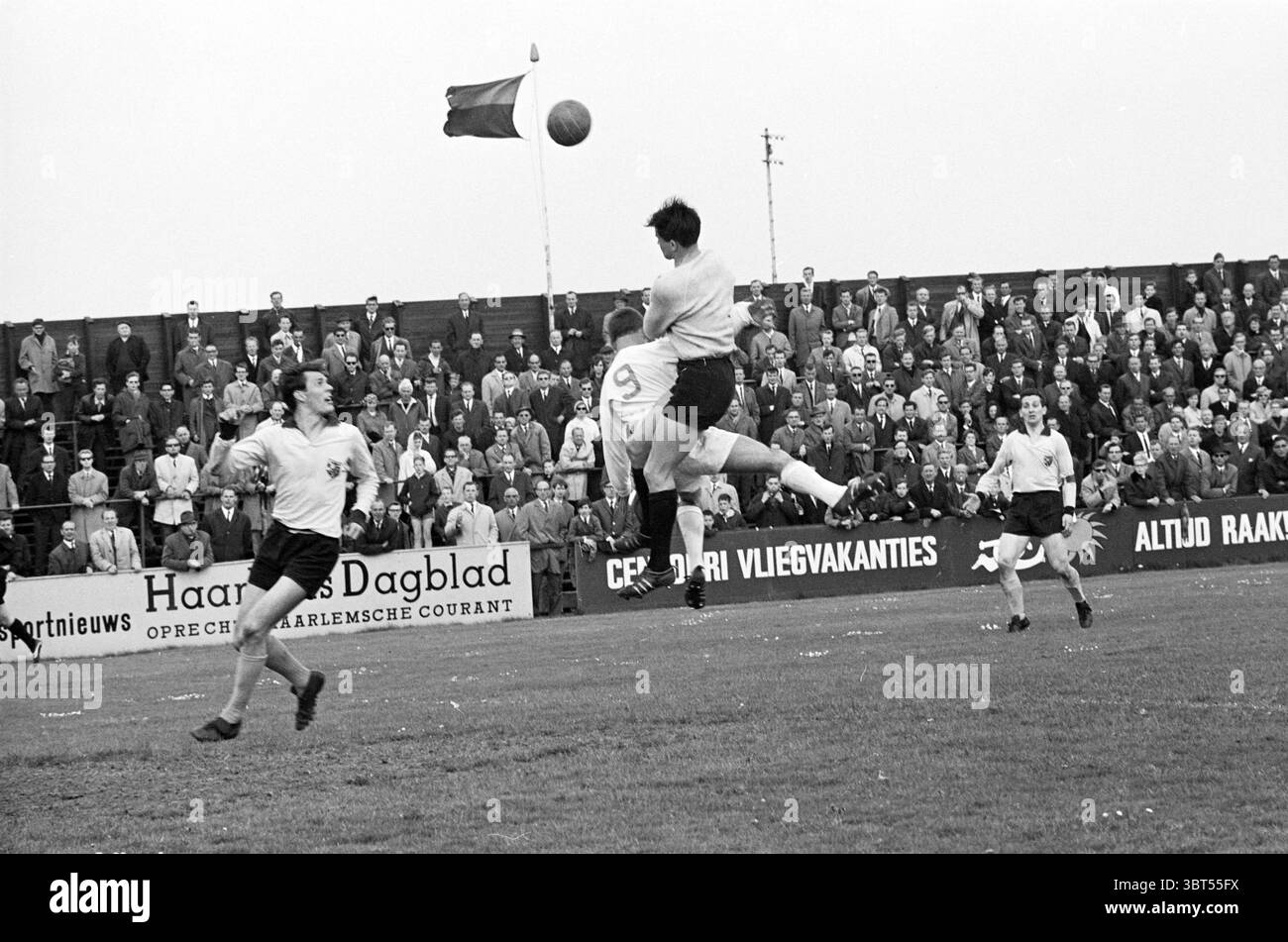 Partita di calcio., Whizgle News, Dutch Desk, Paesi Bassi, 1950 - 2000. Questi sono gli argomenti nell'immagine. La scena raffigura una partita di calcio dinamica che si svolge su un campo erboso. In prima linea, un giocatore con pantaloncini bianchi e una maglia di colore chiaro sta saltando in aria, cercando abilmente di colpire la palla. La sua postura mostra determinazione, con le braccia sollevate per l'equilibrio e la concentrazione diretta verso la palla. Al contrario, un altro giocatore con pantaloncini più scuri e una maglia è posizionato nelle vicinanze, anch'esso impegnato nel gioco ma sembra più radicato, probabilmente preparandosi ad intercettare. Lo sfondo viene riempito W. Foto Stock
