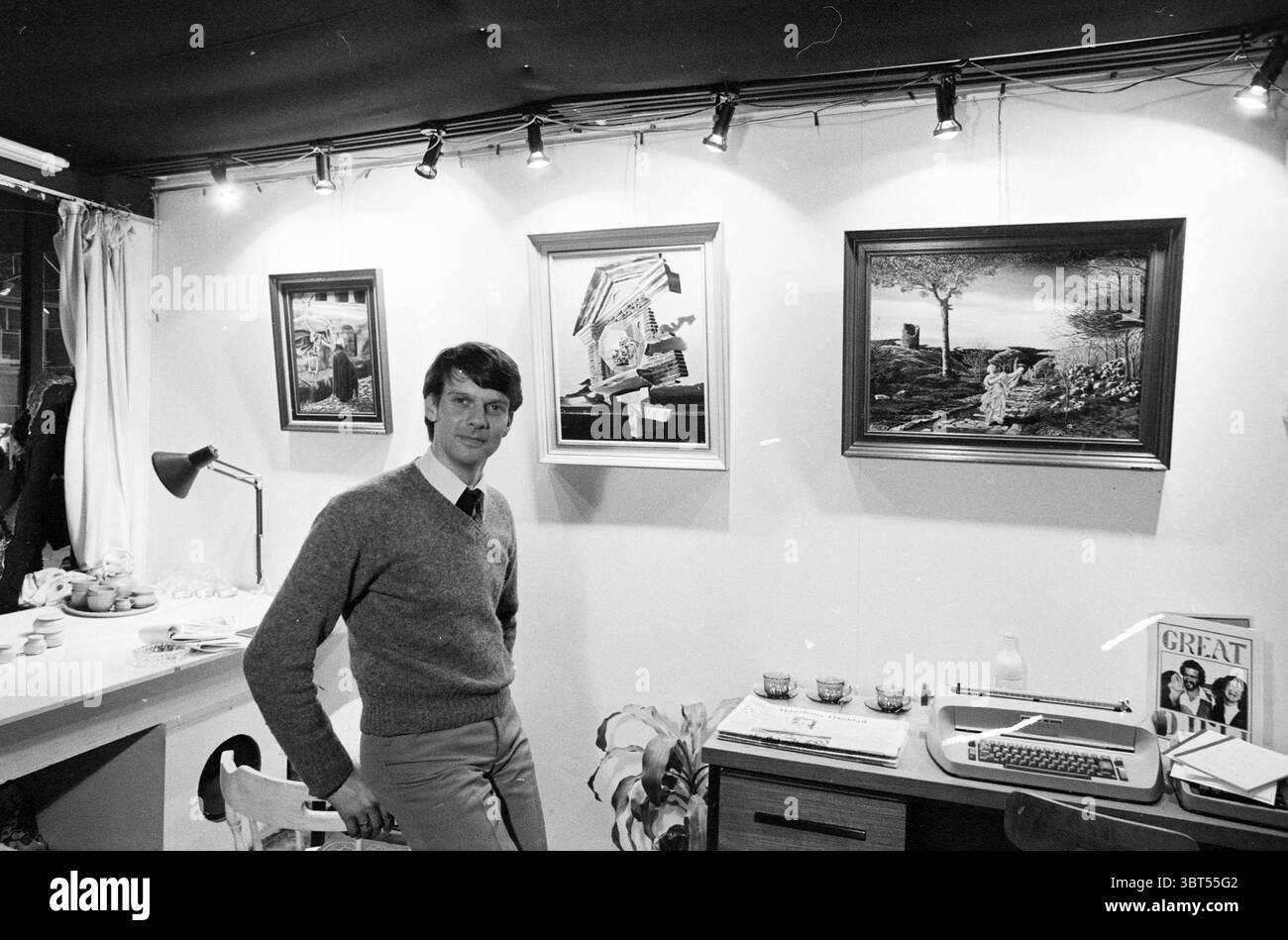 Galerie de AAP + proprietario Lisse Gallery Lisse, Whizgle News, Dutch Desk, Paesi Bassi, 1950 - 2000 il 01-04-1981. Questi argomenti vengono visualizzati nell'immagine. La scena cattura un momento all'interno di uno spazio interno ben illuminato, probabilmente una galleria d'arte o un'esposizione. A sinistra, un piano di lavoro pulito e minimalista presenta una serie di piccoli oggetti decorativi, suggerendo un'esposizione curata. Una moderna lampada angolare irradia un fascio di luce mirato, che si aggiunge all'illuminazione generale. Al centro, un uomo sta in piedi casualmente, trasudando un comportamento rilassato ma deciso. È vestito con un maglione leggero, che contrasta dolcemente Foto Stock