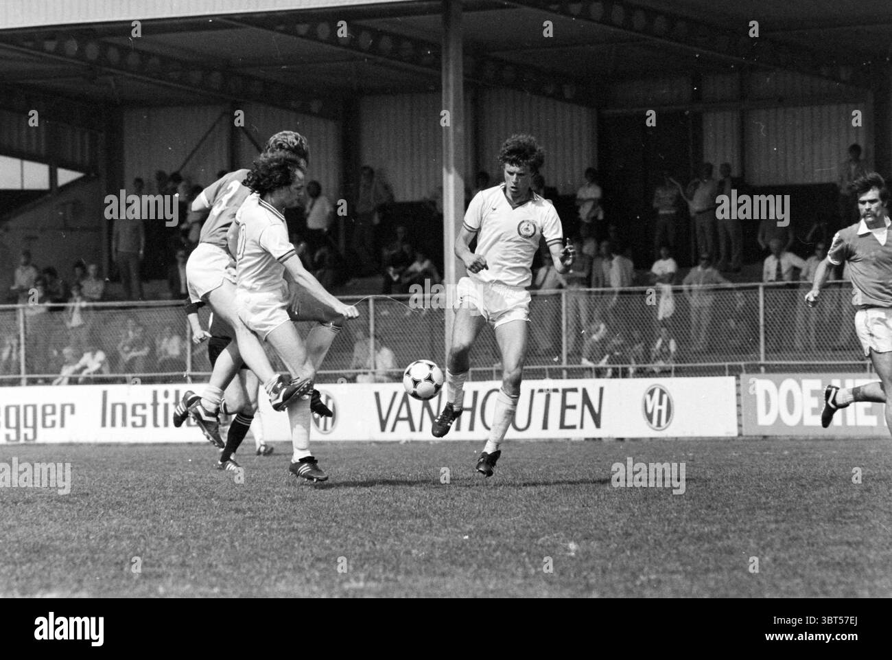 Telstar - Den Bosch Football Telstar, Whizgle News, Dutch Desk, Paesi Bassi, 1950 - 2000 il 10-05-1981. Questi argomenti sono mostrati nell'immagine. La scena cattura un momento dinamico su un campo da calcio erboso, caratterizzato da azione intensa e competizione. In primo piano, tre giocatori sono impegnati in un gioco critico. Un giocatore, che indossa pantaloncini bianchi e una maglietta abbinata, ha una gamba sollevata e controlla sapientemente la palla. La sua espressione riflette la concentrazione e la determinazione. Un altro giocatore, vestito con un'uniforme più scura, sembra essere in movimento, caricando verso la palla con un senso di u Foto Stock