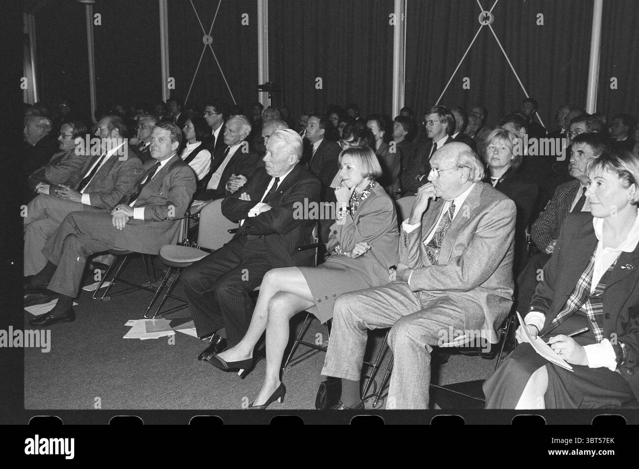 Presentazione Ufficio Provinciale del turismo Olanda settentrionale, Whizgle News, Dutch Desk, Paesi Bassi, 1950 - 2000 il 20-10-1993. L'immagine include questi argomenti. In una conferenza, un grande pubblico è seduto in file di sedie di fronte a un palco o a un altoparlante. La folla è composta prevalentemente da adulti, molti dei quali sono vestiti in abiti da lavoro, riflettendo un'atmosfera formale. Gli individui mostrano un mix di espressioni, alcune appaiono impegnate e altre profondamente nel pensiero, suggerendo una serie di reazioni a tutto ciò che sta accadendo sul palco. L'illuminazione è attenuata, probabilmente da un fissaggio sospeso Foto Stock