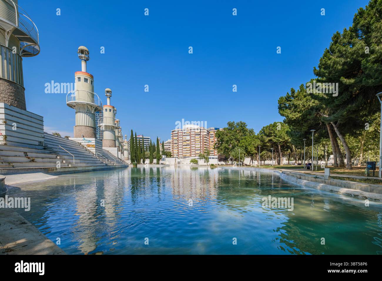 Lago urbano con acqua verde nel Parc Espanya Industrial Barcellona Spagna. Laghetto del parco pubblico, condomini, cipressi, area ricreativa, città Foto Stock