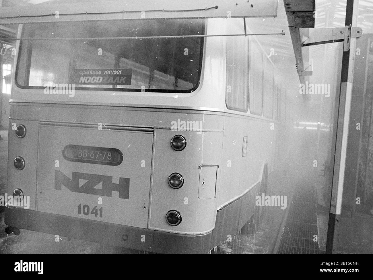 Autobus di manutenzione Leiden Noord Zuid Hollandse Vervoersmaatschappij N.V. NZ, Whizgle News, Dutch Desk, Paesi Bassi, 1950 - 2000 il 17-02-1970. Questi sono gli elementi dell'immagine. La scena presenta un autobus d'epoca che viene lavato in un ambiente industriale. L'autobus, principalmente bianco con un tocco di grigio, si distingue sullo sfondo leggermente sfocato dell'impianto di lavaggio. Sul retro sono presenti marcature audaci e sobrie, tra cui un'importante designazione numerica e un acronimo, che potrebbe rappresentare un'organizzazione o un'azienda. L'ambiente intorno all'autobus è umido e fumante, con il riempimento di nebbia Foto Stock