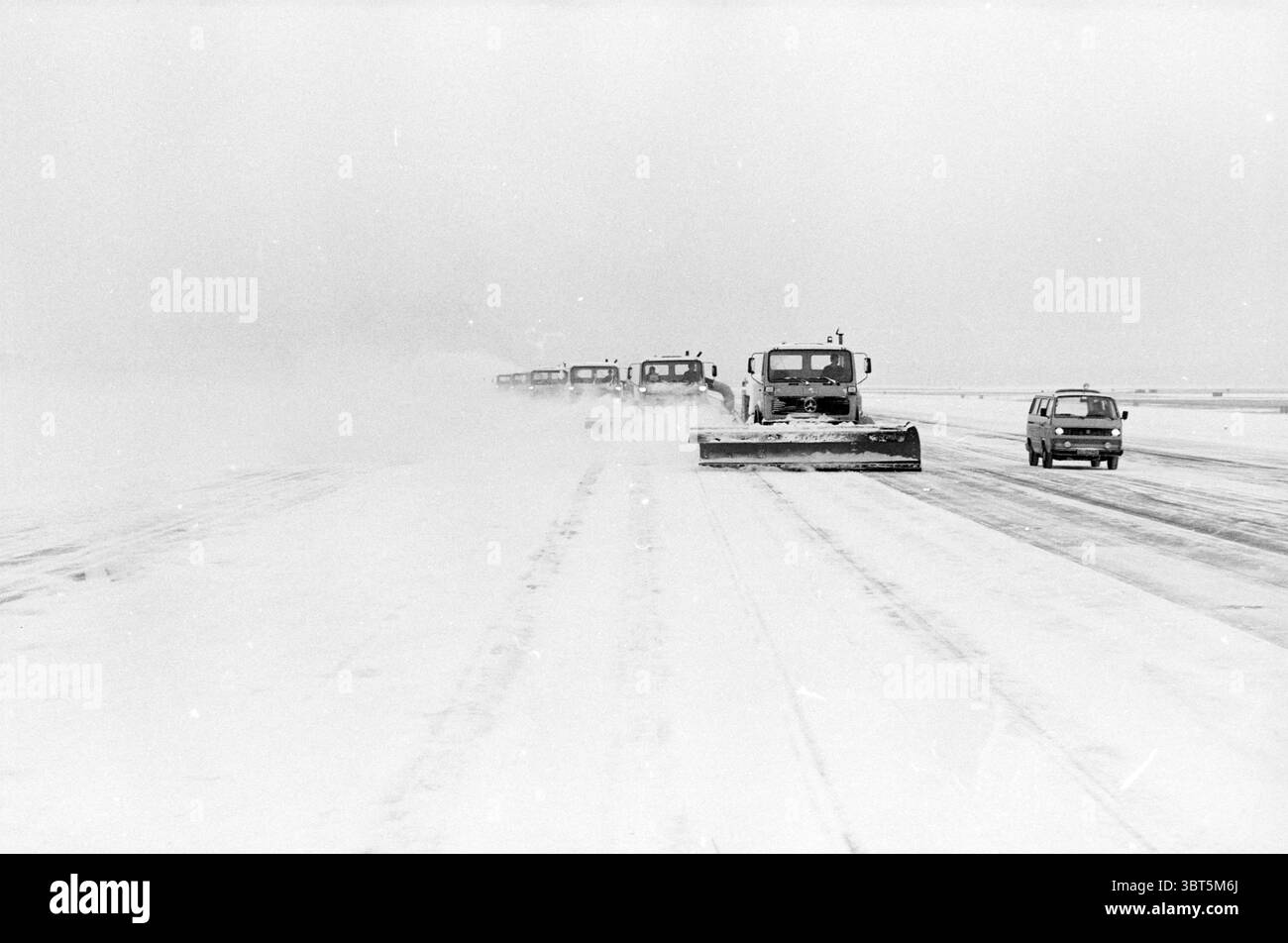 Spazzaneve Schiphol Snow Schiphol Schiphol, Whizgle News, Dutch Desk, Paesi Bassi, 1950 - 2000 il 23-01-1984. Questi argomenti sono mostrati nell'immagine. La scena raffigura un paesaggio invernale sereno ma crudo, dominato da una coperta di neve fresca e bianca che si estende ininterrottamente sul terreno. L'atmosfera è silenziosa, con un cielo coperto che proietta una tonalità grigia su tutto, creando un umore cupo. In primo piano, numerose lame spazzaneve massicce sono impegnative al lavoro e le loro lame grandi spingono efficacemente da parte la neve e sgombrano il percorso. Questi veicoli sono allineati, a dimostrazione di un senso di Foto Stock