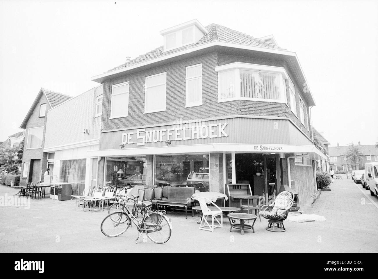 Esterno Wijkerstraatweg 217 Velsen-Noord Velsen-Noord Wijkerstraatweg, Whizgle News, Dutch Desk, Paesi Bassi, 1950 - 2000 il 13-07-1994. Questi argomenti sono mostrati nell'immagine. La scena raffigura un pittoresco edificio d'angolo, caratterizzato dalla sua facciata in mattoni e dall'architettura tradizionale. La struttura si erge in modo prominente e presenta grandi finestre che rivelano un invitante interno pieno di vari mobili, come sedie e tavoli, disposti con cura. Una bicicletta si appoggia sul lato dell'edificio, aggiungendo un tocco di nostalgia all'ambientazione. La tavolozza dei colori è prevalentemente monoc Foto Stock
