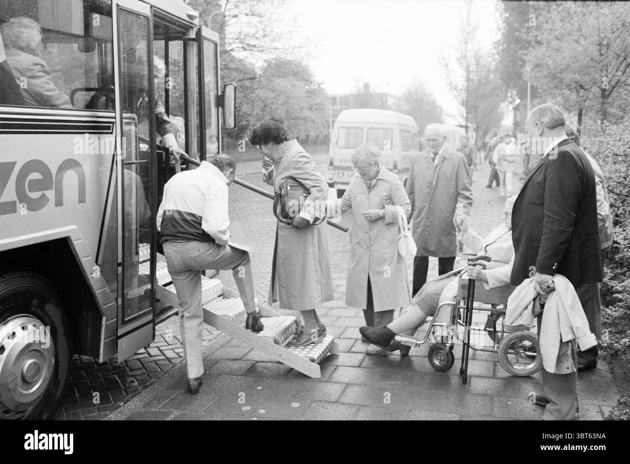 Partenza persone da O.I.G. (relax per disabili) IJmuiden partenza IJmuiden Abelenstraat Paesi Bassi, Whizgle News, Dutch Desk, Paesi Bassi, 1950 - 2000 il 23-05-1985. Questi argomenti vengono visualizzati nell'immagine. La scena cattura un momento presso una fermata dell'autobus, mostrando una varietà di persone coinvolte nel processo di imbarco su un grande autobus. L'autobus stesso ha un accattivante esterno metallico con la parola "cittadino" in evidenza, ma senza entrare nei dettagli dei personaggi all'interno della scena. Occupando il primo piano, un uomo con una tuta di colore chiaro sta salendo sul bu Foto Stock
