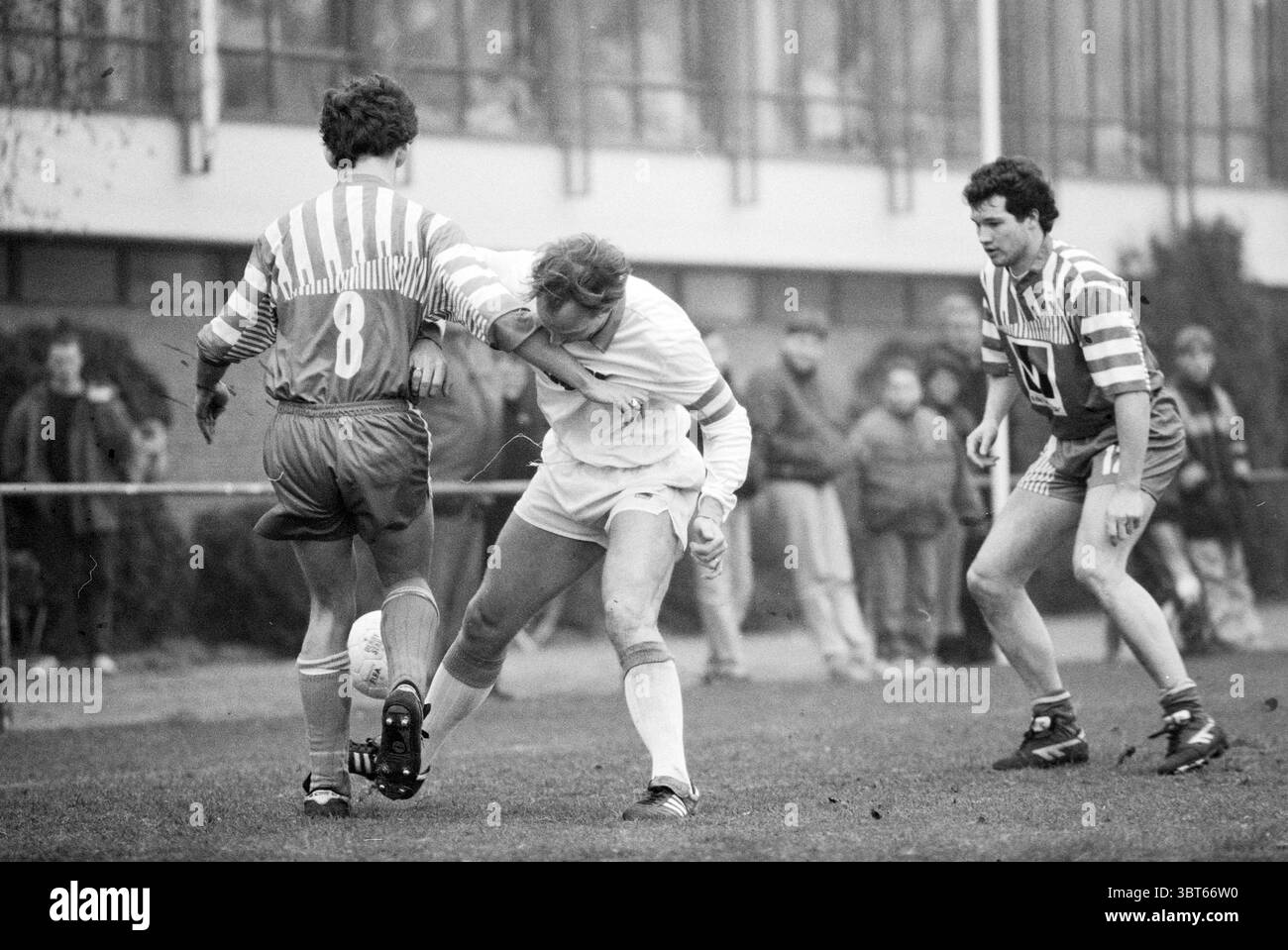 Calcio: Bloemendaal-Velsenoord, Whizgle News, Dutch Desk, Paesi Bassi, 1950 - 2000 il 13-02-1993. L'immagine mostra questi argomenti. La scena cattura un momento dinamico in una partita di calcio, caratterizzato da un senso di intensità e competizione. In primo piano, due giocatori si impegnano attivamente in una lotta per il possesso della palla. Un giocatore, indossando una maglia a righe nelle tonalità del rosso e del bianco, si inclina in avanti con determinazione mentre cerca di superare l'altro, vestito con un'uniforme di colore chiaro con pantaloncini coordinati. Quest'ultima, a metà azione, sembra essere abilmente in grado di eludere una sfida Foto Stock