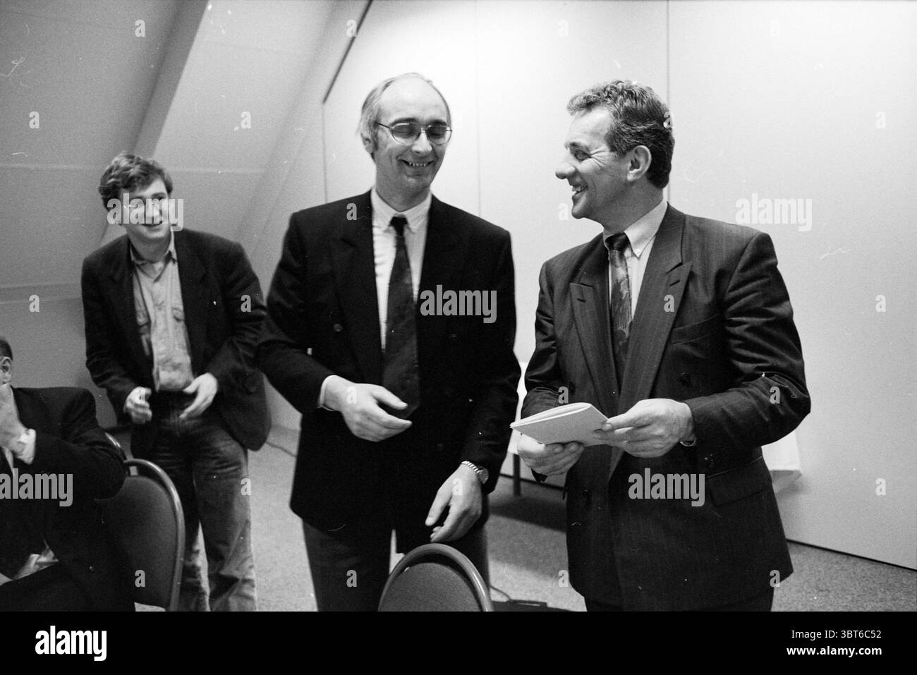 Maiali Farmers Meeting Utrecht Utrecht, Whizgle News, Dutch Desk, Paesi Bassi, 1950 - 2000 il 03-03-1992. L'immagine contiene questi argomenti. La scena vede tre uomini impegnati in una conversazione vivace. Due di loro sono in piedi vicini, mentre il terzo sembra essere leggermente rimosso, osservando l'interazione con un sorriso. L'uomo a sinistra ha un aspetto casual, indossando una giacca grigio chiaro su una camicia più scura. Ha indubbiato capelli scuri e un'espressione amichevole, leggermente inclinato in avanti, a indicare il suo fidanzamento nel momento. Il suo comportamento casuale contrasta con il più formale atti Foto Stock