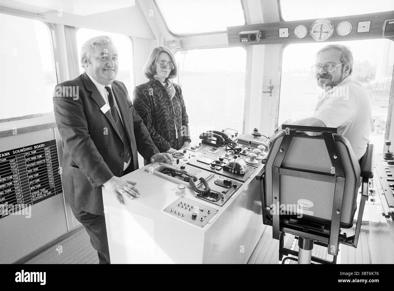 Fornire la barca Sea Forth IJmuiden e varie navi IJmuiden Paesi Bassi, Whizgle News, Dutch Desk, Paesi Bassi, 1950 - 2000 il 29-09-1988. Questi sono gli argomenti nell'immagine. In una stanza luminosa e ben illuminata che assomiglia all'area di controllo di un'imbarcazione, vengono riuniti tre individui, dando alla scena un senso di cameratismo e di scopo. Le pareti sono adornate da vari strumenti e indicatori, che fanno pensare alla navigazione e alle operazioni nautiche. Due persone stanno sul lato sinistro, sorridenti e impegnati in una conversazione. La prima persona, un uomo con i capelli di sale e pepe, indossa una tuta scura Foto Stock