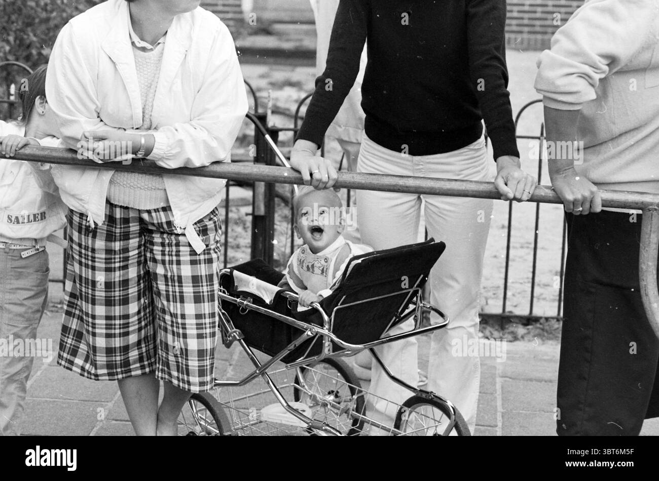 Biciclette decorate a causa della settimana della festa Vijfhuizen biciclette piste ciclabili ciclisti Vijfhuizen, Whizgle News, Dutch Desk, Paesi Bassi, 1950 - 2000 il 11-09-1985. Questi sono gli elementi dell'immagine. La scena presenta un gruppo di individui riuniti da vicino, caratterizzati da una varietà di stili di abbigliamento che riflettono un'epoca passata. A sinistra, una donna è vestita con una giacca di colore chiaro, a strati su una blusa bianca e una gonna a quadri con un mix di toni tenui, composta principalmente da verdi scuri e rossi. La sua posizione è rilassata ma impegnata, poichè si appoggia leggermente su una ringhiera di legno. Avanti Foto Stock Biciclette decorate a causa della settimana della festa Vijfhuizen biciclette piste ciclabili ciclisti Vijfhuizen, Whizgle News, Dutch Desk, Paesi Bassi, 1950 - 2000 il 11-09-1985. Questi sono gli elementi dell'immagine. La scena presenta un gruppo di individui riuniti da vicino, caratterizzati da una varietà di stili di abbigliamento che riflettono un'epoca passata. A sinistra, una donna è vestita con una giacca di colore chiaro, a strati su una blusa bianca e una gonna a quadri con un mix di toni tenui, composta principalmente da verdi scuri e rossi. La sua posizione è rilassata ma impegnata, poichè si appoggia leggermente su una ringhiera di legno. Avanti Foto Stock