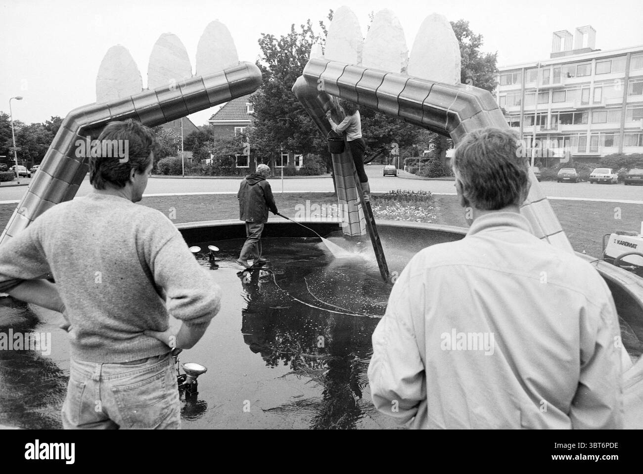 Fontana su Valkenburgerplein Heemstede Valkenburgerplein Paesi Bassi, Whizgle News, Dutch Desk, Paesi Bassi, 1950 - 2000 il 22-06-1992. Questi argomenti sono mostrati nell'immagine. La scena cattura un'impressionante installazione urbana che assomiglia a una grande e giocosa fontana a forma di denti esagerati e sovradimensionati. La struttura è prevalentemente argentata, mescolando elementi di metallo con vivaci spruzzi di colore dall'acqua che precipita verso il basso. Tre persone stanno a stretto contatto in primo piano e le loro espressioni trasmettono curiosità e coinvolgimento con l'installazione. Le prime due cifre lo sono Foto Stock Fontana su Valkenburgerplein Heemstede Valkenburgerplein Paesi Bassi, Whizgle News, Dutch Desk, Paesi Bassi, 1950 - 2000 il 22-06-1992. Questi argomenti sono mostrati nell'immagine. La scena cattura un'impressionante installazione urbana che assomiglia a una grande e giocosa fontana a forma di denti esagerati e sovradimensionati. La struttura è prevalentemente argentata, mescolando elementi di metallo con vivaci spruzzi di colore dall'acqua che precipita verso il basso. Tre persone stanno a stretto contatto in primo piano e le loro espressioni trasmettono curiosità e coinvolgimento con l'installazione. Le prime due cifre lo sono Foto Stock