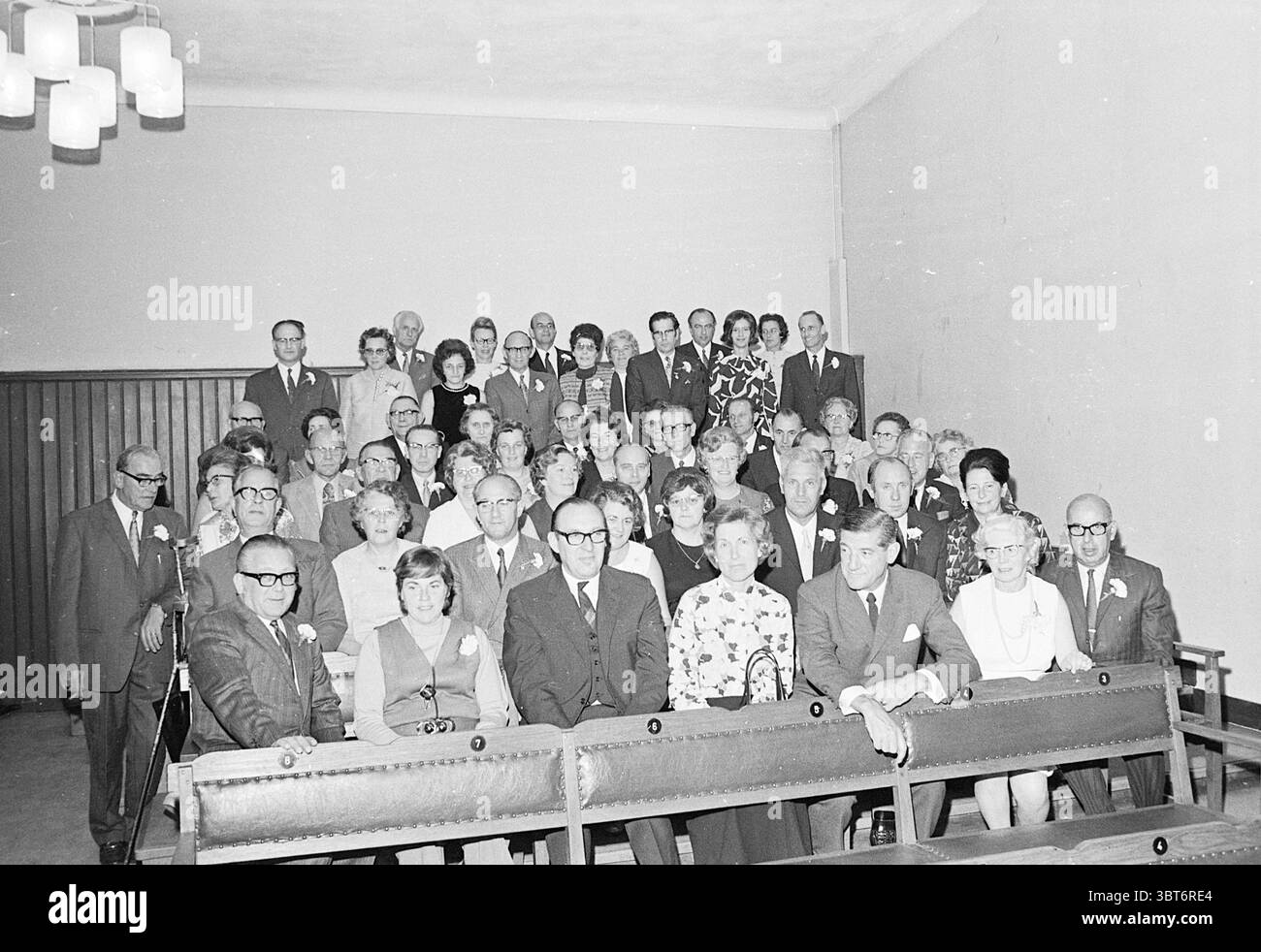 Serata party NZH Haarlem Noord Zuid Hollandse Vervoersmaatschappij N.V. NZ, Whizgle News, Dutch Desk, Paesi Bassi, 1950 - 2000 il 11-10-1971. L'immagine mostra questi argomenti. La scena cattura un grande gruppo di persone riunite in un interno spazioso, probabilmente una sala o un centro comunitario. Lo sfondo è una parete di colore chiaro, che contribuisce a creare un tono generale morbido e neutro. Seduti in file ordinate, gli individui hanno un'età variabile, suggerendo un mix di famiglie e amici. Il gruppo è vestito con abiti tipici delle occasioni formali della metà del XX secolo, con molti uomini che indossano abiti e cravatte, e donne io Foto Stock