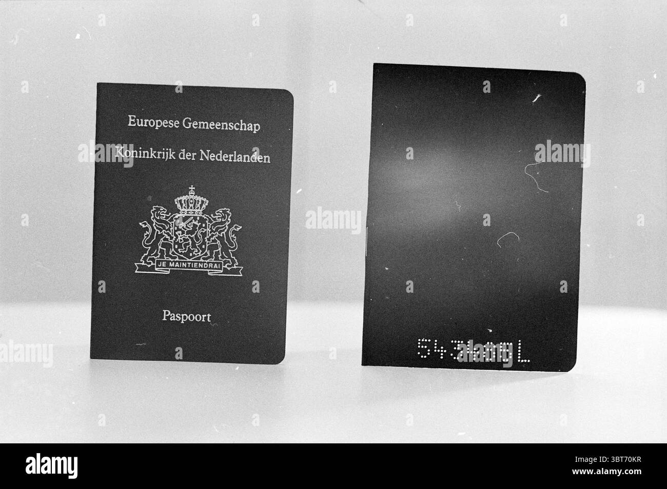 Passaporto vecchio + nuovo Miscellaneous, Whizgle News, Dutch Desk, Paesi Bassi, 1950 - 2000 il 16-10-1989. Questi argomenti vengono visualizzati nell'immagine. La scenografia presenta due passaporti visualizzati fianco a fianco. Il passaporto sulla sinistra ha una profonda e ricca copertura blu navy adornata con eleganti dettagli dorati in rilievo, tra cui un emblema reale al centro. L'emblema, dettagliato e intricato, suggerisce autorità e patrimonio. Il coperchio sembra avere una superficie leggermente ruvida, che gli conferisce un senso di profondità. Il passaporto a destra, in contrasto con la sua semplicità, ha una copertura nera solida che è liscia e non adorne Foto Stock