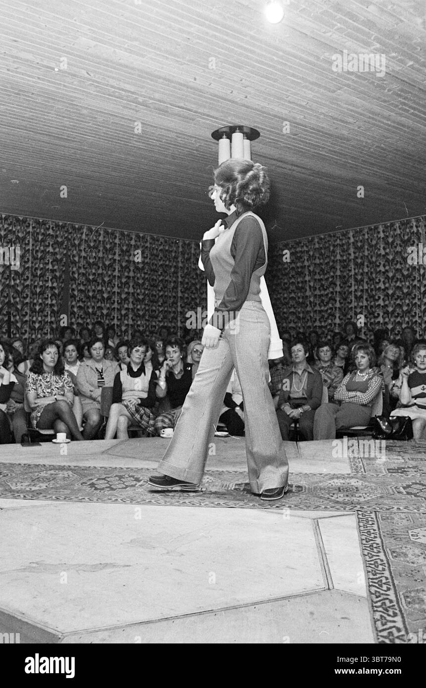 Centro commerciale per le sfilate di moda Schalkwijk Fashion Show, Whizgle News, Dutch Desk, Paesi Bassi, 1950 - 2000 il 10-04-1973. Questi sono gli elementi dell'immagine. La scena cattura un vivace evento di moda in un ambiente interno spazioso. Al centro dell'attenzione c'è un modello, che si muove con sicurezza lungo una pista. Indossa abiti aderenti che enfatizzano la sua silhouette; un top elegante abbinato a pantaloni svasati che rispecchiano un'estetica vintage. I suoi capelli sono modellati voluminosamente, contribuendo all'energia dinamica del momento. L'impostazione è decorata con uno sfondo a ripetizione che aggiunge texture e profondità al Foto Stock