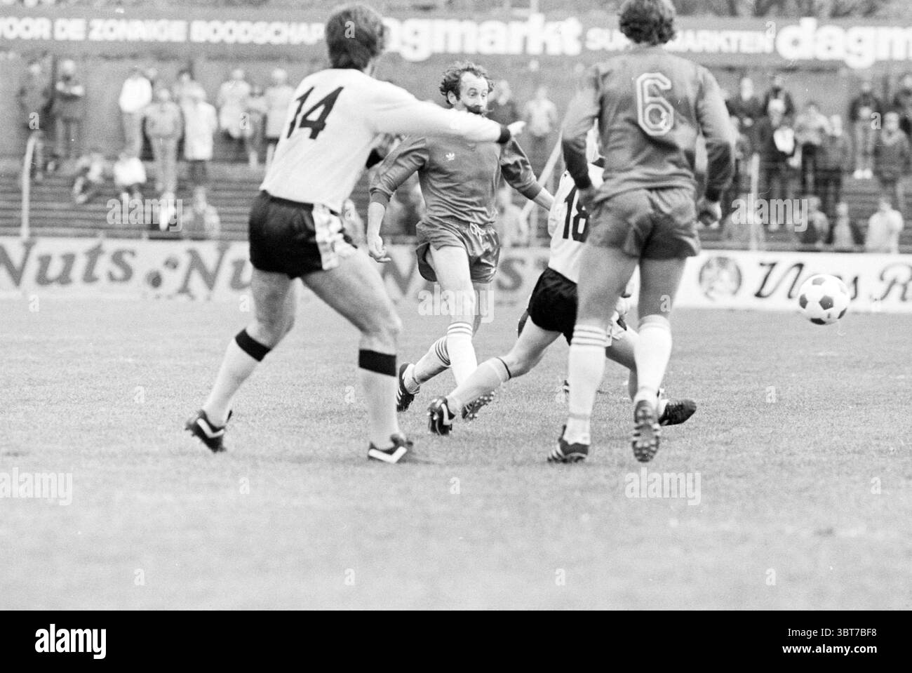 Partita di calcio HFC Haarlem - NEC Haarlem Nederland, Whizgle News, Dutch Desk, Paesi Bassi, 1950 - 2000 il 04-05-1980. Questi argomenti vengono visualizzati nell'immagine. In una dinamica scena sportiva all'aperto, un gruppo di atleti è impegnato in una partita di calcio su un campo erboso. Due giocatori sono chiaramente in azione: Uno, con una maglia blu e posizionato centralmente, è pronto ad intercettare una palla da calcio rotolante. Sta mostrando concentrazione, con gli occhi ben concentrati sulla palla mentre si prepara per la sua prossima mossa. Intorno a lui ci sono diversi compagni di squadra e avversari vestiti con uniformi contrastanti. A destra, Foto Stock