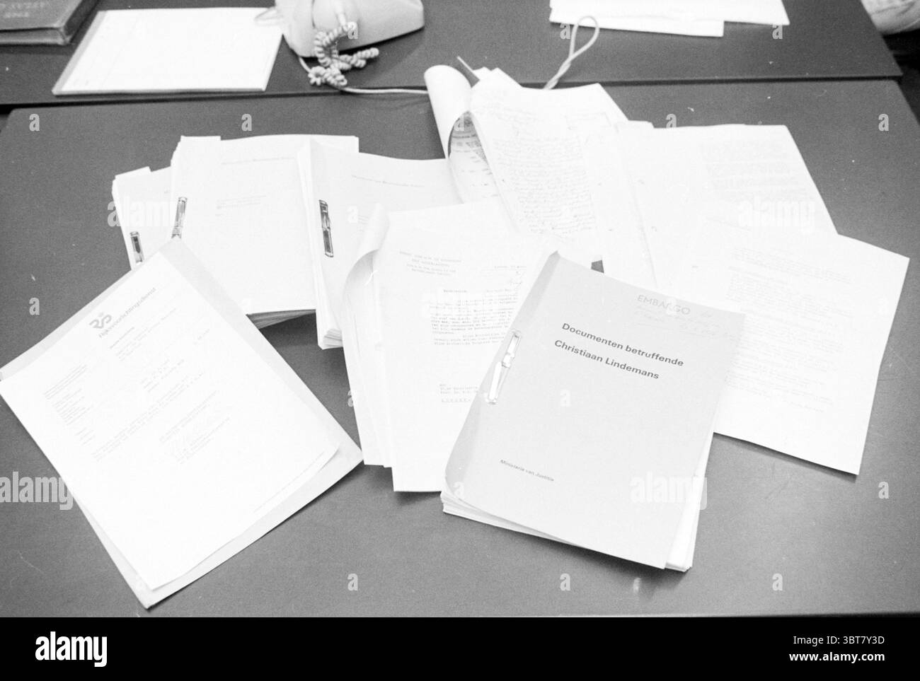 File King Kong War Remains, Whizgle News, Dutch Desk, Paesi Bassi, 1950 - 2000 il 21-03-1986. L'immagine contiene questi argomenti. La scena visiva raffigura un'area di lavoro ingombrante dominata da una serie di documenti sparsi su una superficie scura. Le carte di varie dimensioni sono disposte in modo casuale, alcune stropicciate mentre altre sono impilate con cura. Una cartella prominente, distinguibile per la sua rilegatura più spessa, si trova in alto, parzialmente aperta per rivelarne il contenuto. La tavolozza dei colori è prevalentemente monocromatica, con sfumature di bianco, bianco sporco e grigio, offrendo un senso di minimalismo in mezzo al caos. Foto Stock