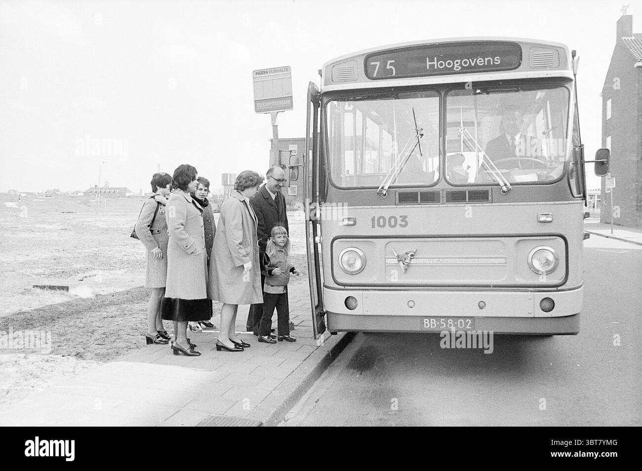 Anniversario con l'autobus NZH Noord Zuid Hollandse Vervoersmaatschappij N.V. NZ, Whizgle News, Dutch Desk, Paesi Bassi, 1950 - 2000 il 26-04-1971. L'immagine contiene questi argomenti. In un vivace ambiente urbano, un autobus d'epoca è parcheggiato lungo un marciapiede, con la parte anteriore leggermente inclinata verso lo spettatore. L'autobus e' dipinto in uno schema colore arancio e crema sbiadito, donandogli un'atmosfera retrò. Il display della destinazione recita "75 Hoogovens", contribuendo alla narrazione della scena. Un gruppo di sei persone si trova sul marciapiede, riunendosi vicino all'autobus. Variano in età, suggerendo un mix di famiglie o amici Foto Stock