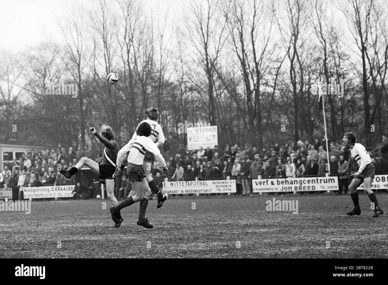 Partita di calcio., Whizgle News, Dutch Desk, Paesi Bassi, 1950 - 2000. Questi argomenti vengono visualizzati nell'immagine. La scena raffigura un momento dinamico su un campo da calcio, in cui i giocatori sono impegnati in una partita intensa. In primo piano, un giocatore eseguì un calcio potente, facendo volare la palla in aria. La sua postura suggerisce determinazione e atletismo, con muscoli tesi e occhi concentrati sulla traiettoria della palla. Intorno a lui ci sono un paio di compagni di squadra e avversari, ciascuno in movimento, impegnati nel gioco. Le loro espressioni trasmettono concentrazione e spirito competitivo. I giocatori sono dres Foto Stock
