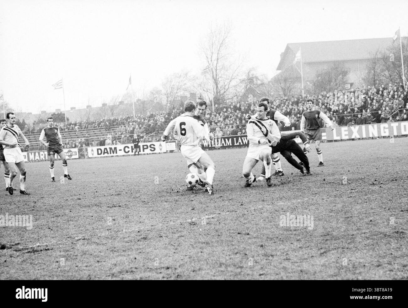 Haarlem - Veendam Football Haarlem, Whizgle News, Dutch Desk, Paesi Bassi, 1950 - 2000 il 12-01-1969. Questi argomenti vengono visualizzati nell'immagine. La scena cattura un momento emozionante su un campo di calcio, pieno di azione. Diversi giocatori nelle tradizionali divise da calcio sono impegnati in un gioco dinamico; un giocatore, indossando il numero 6, sta manovrando abilmente con la palla, mentre due avversari convergono su di lui, tentando di ottenere il possesso. Le loro uniformi sono distinte, con colori contrastanti (tonalità chiare e scure) che aumentano la tensione della competizione. L'impostazione presenta un pitc erboso Foto Stock