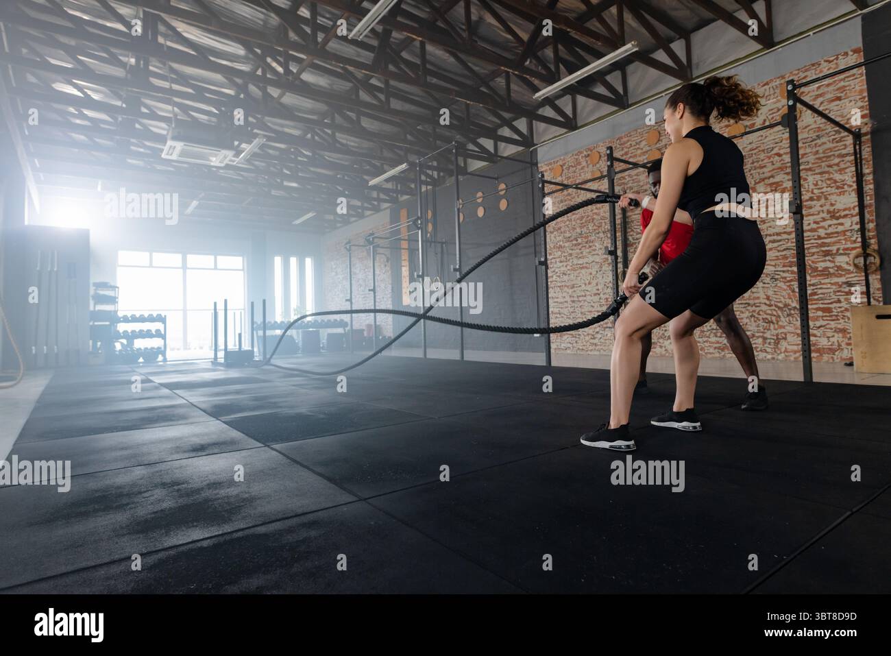 Donna partner di allenamento e uomo afroamericano che usano corde da battaglia in palestra, spazio copia Foto Stock Donna partner di allenamento e uomo afroamericano che usano corde da battaglia in palestra, spazio copia Foto Stock
