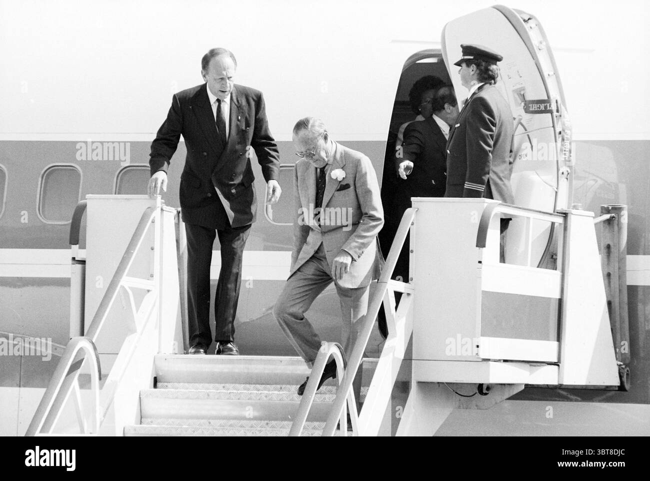 Battesimo 2 Air Holland Aircraft di Prince Bernhard Christening cerimonies Airplanes, Whizgle News, Dutch Desk, Paesi Bassi, 1950 - 2000 il 09-05-1989. Questi sono gli elementi dell'immagine. Sulla scena, un gruppo di individui è visto sbarcare da un aereo. Due uomini stanno scendendo una serie di gradini che portano dall'aereo al suolo. Il primo uomo, vestito con un abito scuro, trasuda un'aria di autorità e sembra guidare il secondo uomo, che è vestito con un vestito più leggero e indossa un fiore bianco sul suo bavero, indicando un'occasione formale. Il secondo uomo sembra un po' più vecchio, con Foto Stock
