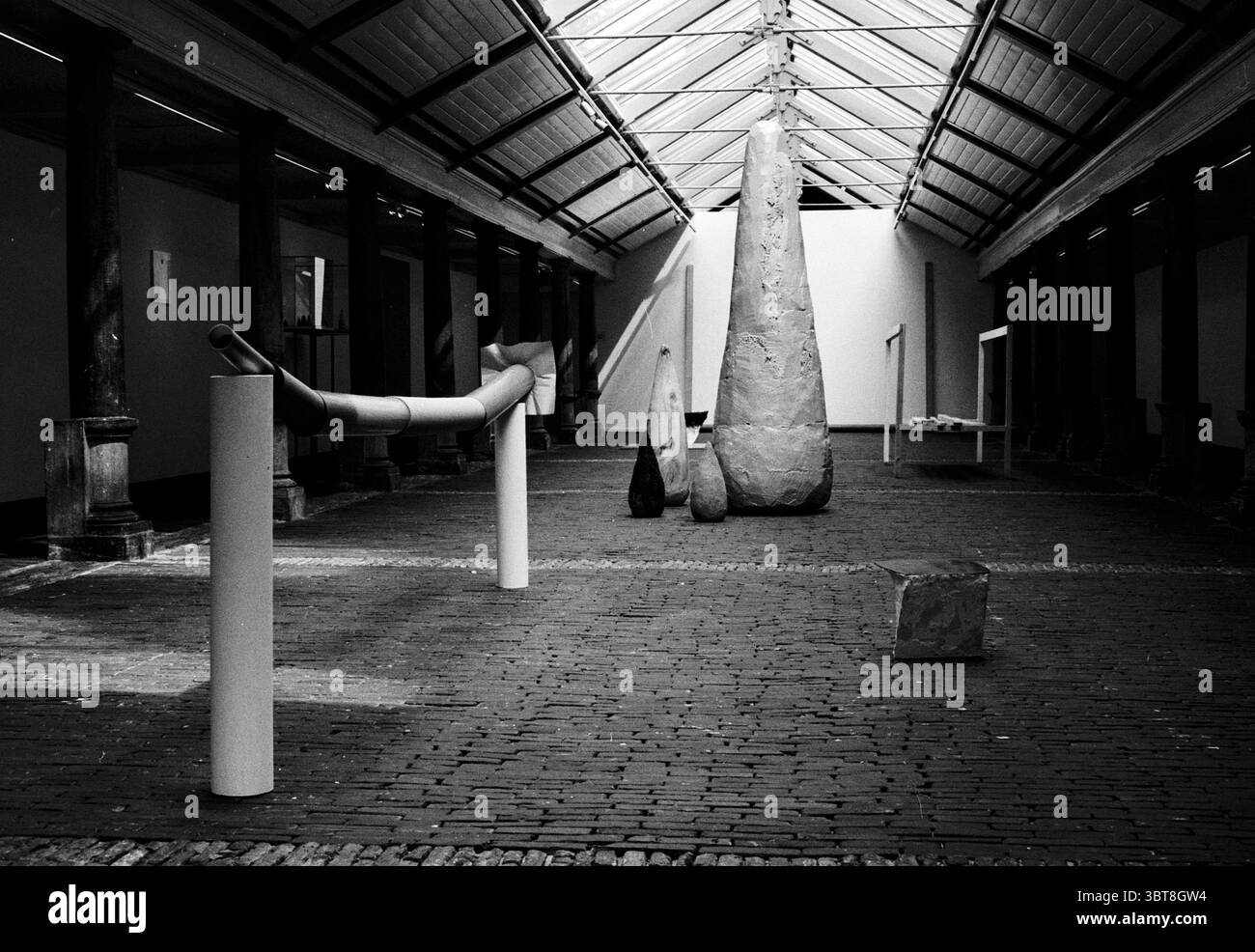 3 x Art Vishal Haarlem Haarlem Grote Markt Paesi Bassi, Whizgle News, Dutch Desk, Paesi Bassi, 1950 - 2000 il 24-07-1994. Questi sono gli argomenti nell'immagine. La scena presenta una spaziosa galleria interna caratterizzata da alti soffitti e un ambiente luminoso e arioso. La luce naturale si riversa attraverso grandi lucernari, proiettando ombre tenui e mettendo in risalto le texture di varie opere d'arte sparse in tutta la sala. Il pavimento è costituito da mattoni dai toni caldi, disposti in un motivo a spina di pesce, che contribuisce al fascino rustico dello spazio. Al centro, una collezione di sculture astratte Foto Stock