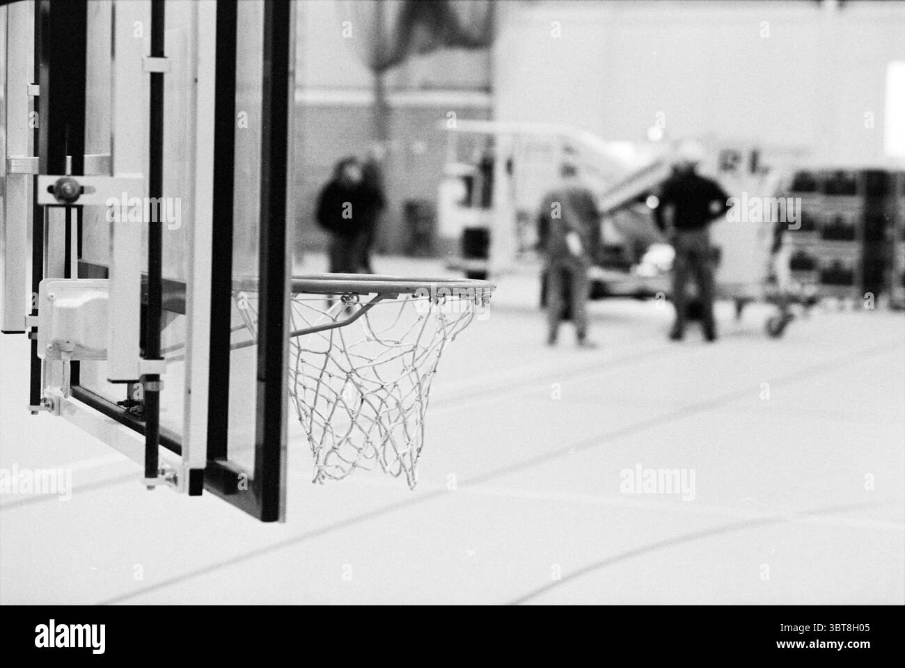 Costruzione della sala CIO, Whizgle News, Dutch Desk, Paesi Bassi, 1950 - 2000 il 21-12-1993. Questi sono gli argomenti nell'immagine. In una spaziosa palestra, il primo piano presenta un canestro da basket, la sua rete leggermente ondeggiante. La struttura metallica del cerchio risplende sotto le luci superiori, che proiettano un soffice bagliore sul pavimento in legno lucido. Lo sfondo rivela due personaggi impegnati nella conversazione, le loro silhouette leggermente sfocate, suggerendo un senso di profondità e distanza. I colori della scena sono prevalentemente attenuati, con sfumature di grigio e sottili accenni di calore dal pavimento in legno e dal TH Foto Stock