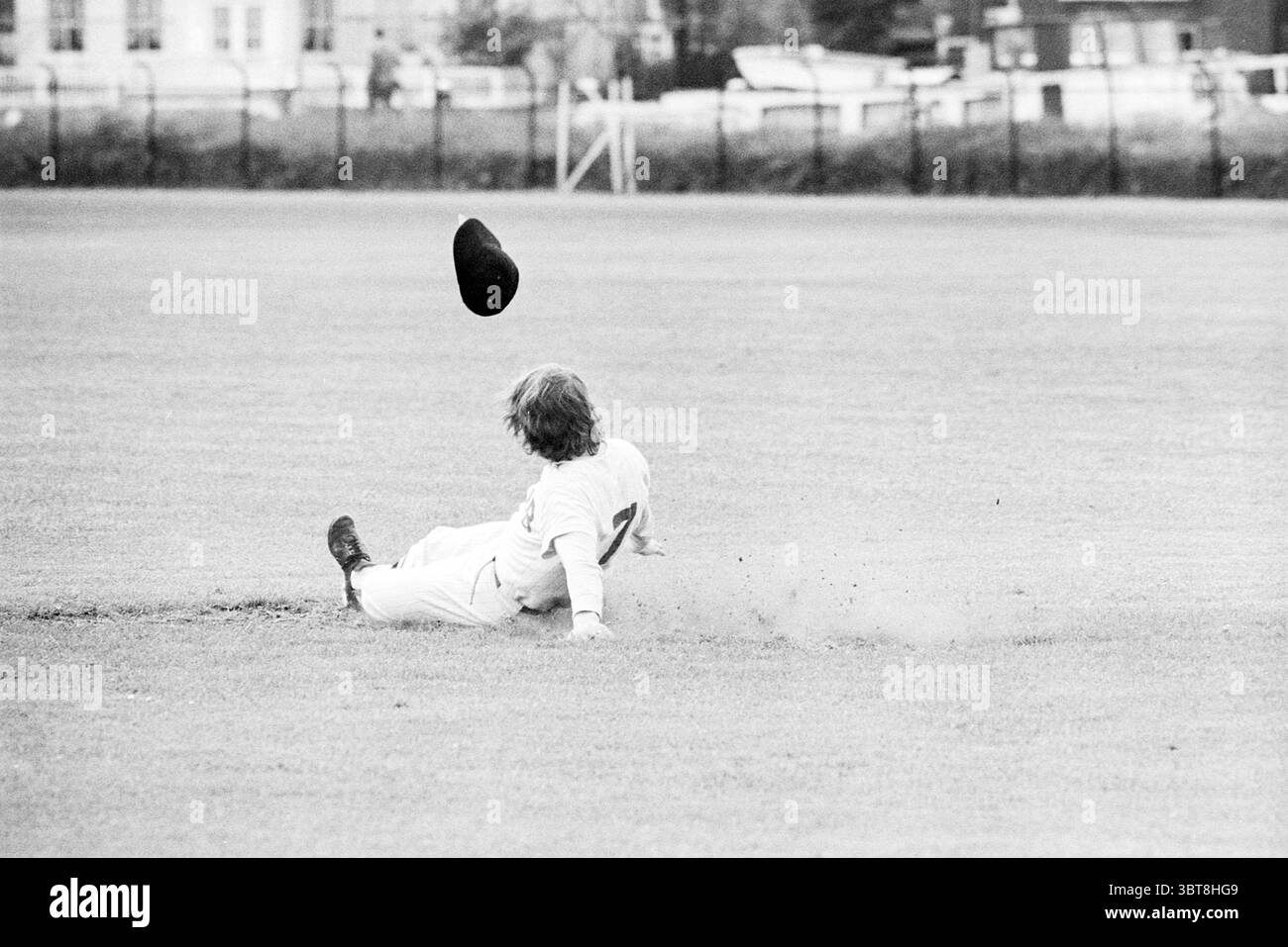 Tybb-Lijnden Baseball, Whizgle News, Dutch Desk, Paesi Bassi, 1950 - 2000 il 03-06-1972. L'immagine mostra questi argomenti. La scena cattura un momento dinamico su un campo erboso, in cui una persona si trova nel bel mezzo di un'azione sportiva. Vestite con un'uniforme di colore chiaro, scivolano a terra, con una gamba allungata in avanti e l'altra nascosta sotto di loro. I loro capelli sono durati, suggerendo l'intensità del movimento. Sopra di essi è presente un tappo scuro, probabilmente spostato durante il vetrino. L'erba è un verde ricco, che contrasta con i toni più chiari della divisa e con macchie di sporco Foto Stock