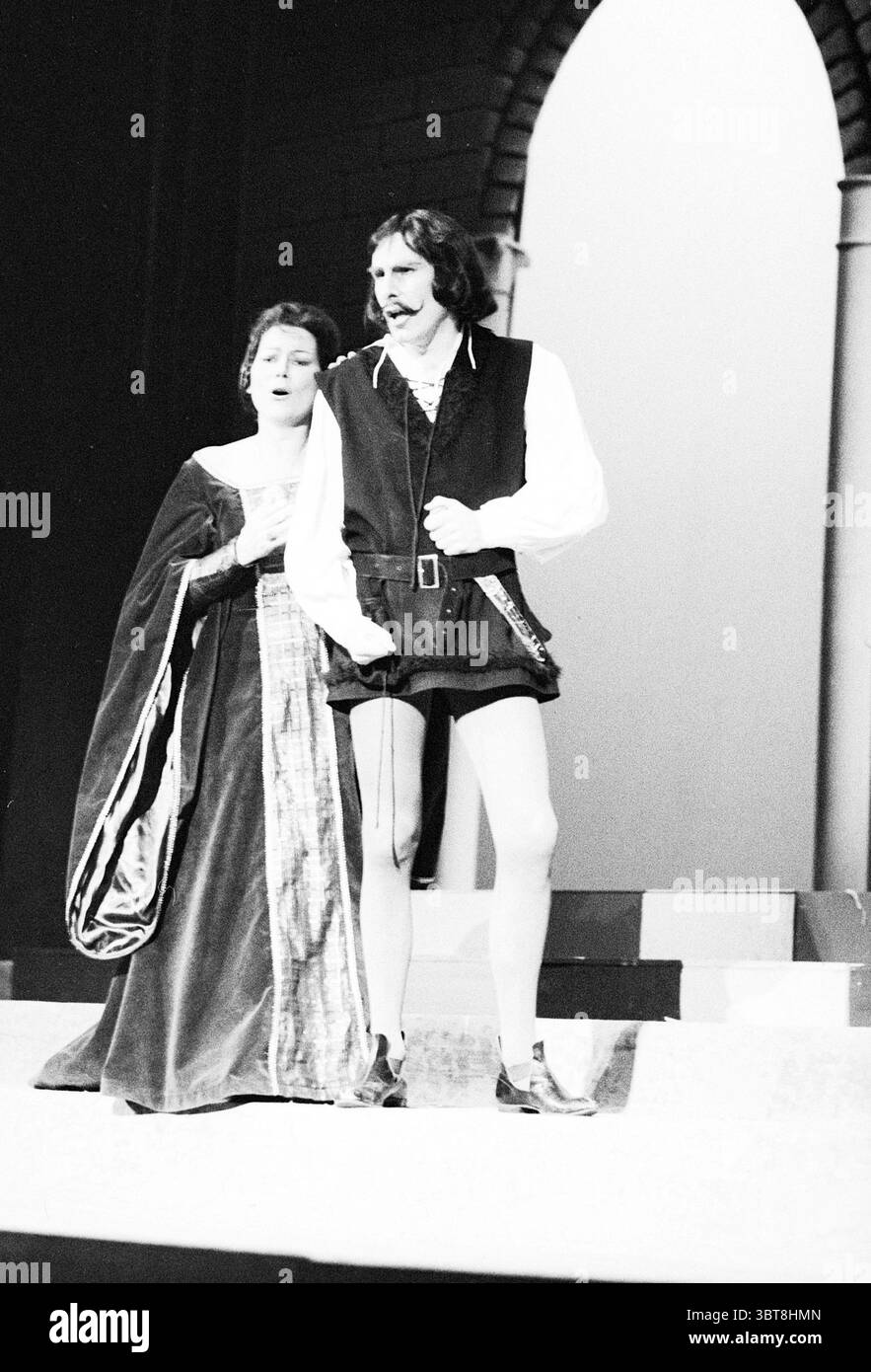 Opera: Il Pirata Bellini Opera operetta, Whizgle News, Dutch Desk, Paesi Bassi, 1950 - 2000 il 09-11-1977. Questi argomenti sono mostrati nell'immagine. La scena raffigura un momento drammatico in uno spettacolo teatrale, catturato in bianco e nero, che aumenta l'intensità emotiva. Due figure dominano il palcoscenico: Una donna e un uomo, entrambi vestiti con abiti d'epoca che suggeriscono un ambiente storico o classico. La donna sta leggermente dietro l'uomo, la sua espressione trasmette un mix di preoccupazione e desiderio. Indossa un ricco abito che scorre a cascata intorno ai suoi piedi, il tessuto scuro con intricati Foto Stock