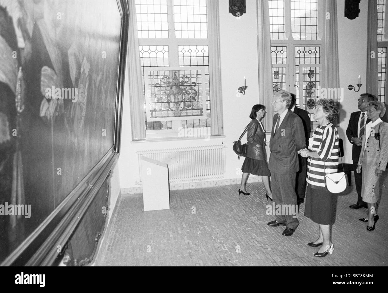 Visita diplomatici e ministri al Museo Frans Hals Museo Frans Hals Haarlem Groot Heiligland Paesi Bassi, Whizgle News, Dutch Desk, Paesi Bassi, 1950 - 2000 il 10-06-1988. L'immagine include questi argomenti. In una grande sala con alti soffitti e grandi finestre ad arco che consentono alla luce naturale di filtrare, un gruppo di individui si erge davanti a un'impressionante opera d'arte. Le pareti sono adornate da intricate modanature e suggeriscono un'aria di storia. Il pavimento è realizzato con piastrelle dai toni caldi, che si aggiungono all'atmosfera classica della camera. Il punto focale della scena è un grande dipinto con cornice scura Foto Stock