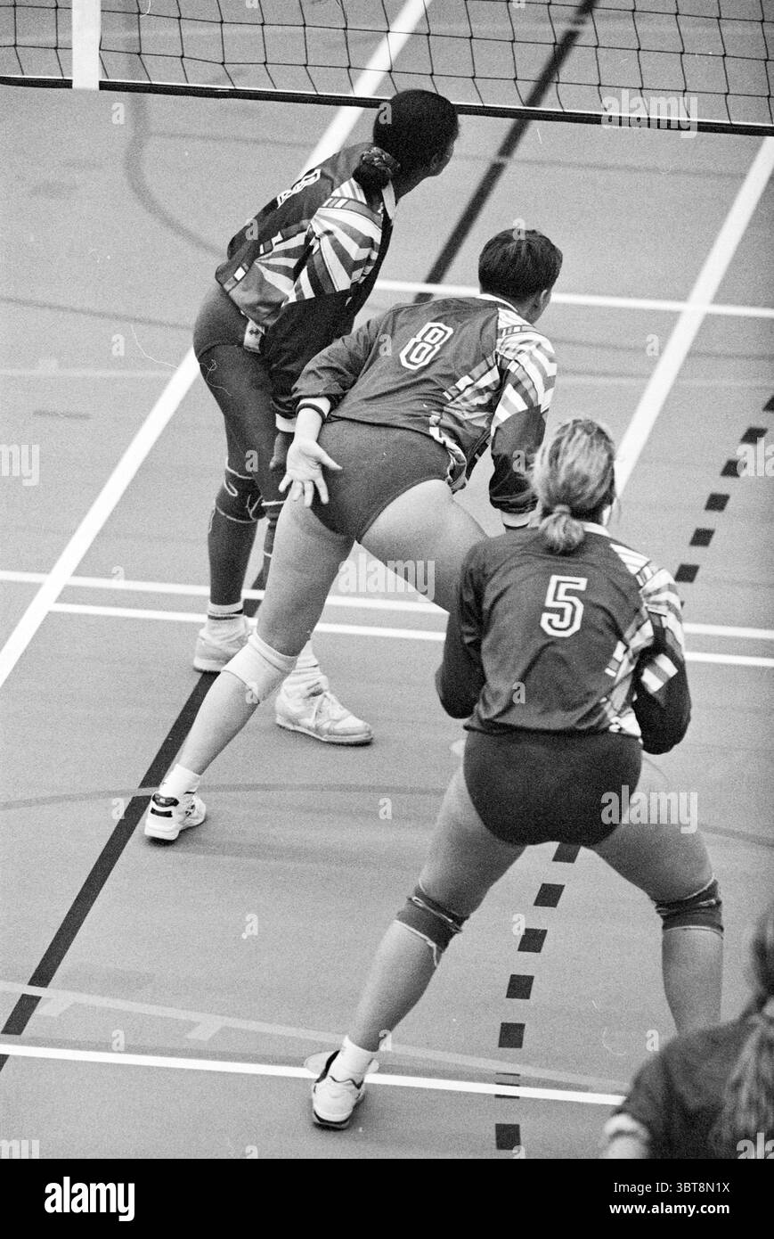 Pallavolo Allides - Krovo, Whizgle News, Dutch Desk, Paesi Bassi, 1950 - 2000 il 03-02-1995. L'immagine include questi argomenti. Nella scena, tre giocatori di pallavolo sono pronti e concentrati sul campo, pronti all'azione. I giocatori sono rivestiti di uniformi atletiche, ognuna caratterizzata da colori audaci e motivi distintivi che enfatizzano la loro individualità, pur mantenendo un aspetto di squadra coeso. Le uniformi mostrano i numeri sul retro, che aiutano a distinguere i giocatori. Le sfumature contrastanti delle loro uniformi creano un impatto visivo dinamico. L'ambiente è un'arena sportiva al coperto, caratteristica Foto Stock
