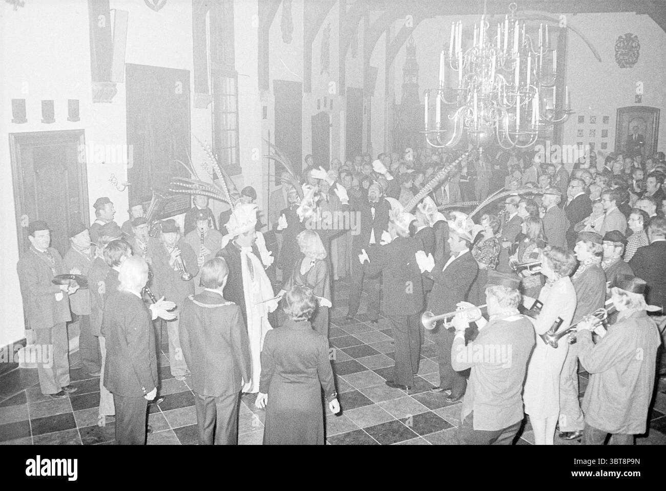 Ricevimento di Capodanno del college Haarlem a Gravenzaal Haarlem Paesi Bassi, Whizgle News, Dutch Desk, Paesi Bassi, 1950 - 2000 il 02-01-1978. Questi argomenti vengono visualizzati nell'immagine. In una grande sala caratterizzata da alti soffitti e eleganti dettagli architettonici, si svolge una vivace festa. Un luminoso lampadario pende dal soffitto, illuminando la scena con una luce calda e soffusa, in contrasto con le sfumature più scure delle pareti e del pavimento della stanza. Il pavimento presenta piastrelle scure che aggiungono un tocco formale all'atmosfera. Le persone sono riunite in gruppi, alcune sono impegnate in una conversazione animata Foto Stock