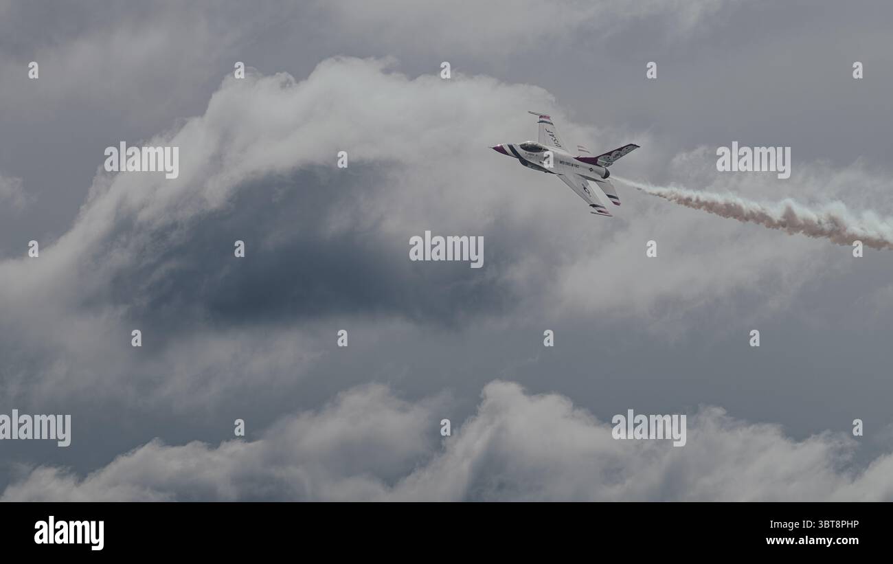 L'USAF Thunderbirds F-16 esegue una salita invertita con pista di fumo contro le nuvole drammatiche al McGuire AFB Airshow, 2025 maggio 2025. Foto Stock