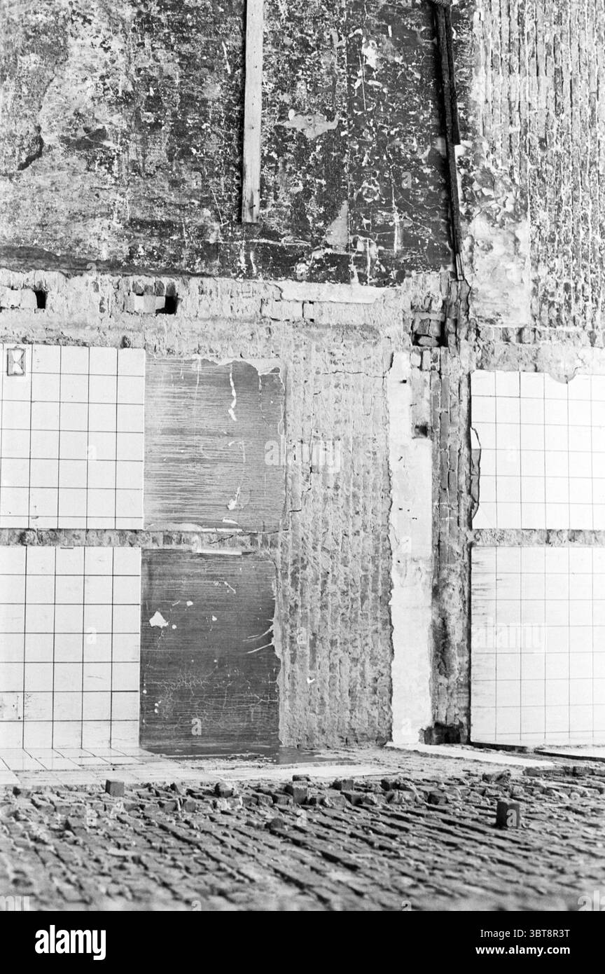 Proprietà arbitrale Lommelaars Koningstraat Case e costruzione di case, Whizgle News, Dutch Desk, Paesi Bassi, 1950 - 2000 il 19-11-1975. Questi argomenti vengono visualizzati nell'immagine. La scena presenta una parete testurizzata che racconta la storia dell'età e dell'usura. La parete presenta una combinazione di mattoni grezzi e a vista e sezioni coperte da quelle che sembrano essere piastrelle quadrate, alcune delle quali sono incrinate o mancanti, rivelando ulteriormente il materiale sottostante. Le piastrelle sono disposte in un disegno a griglia, alternando tra superfici bianche e leggermente usurate, dando un senso di struttura in mezzo al caos. TH Foto Stock