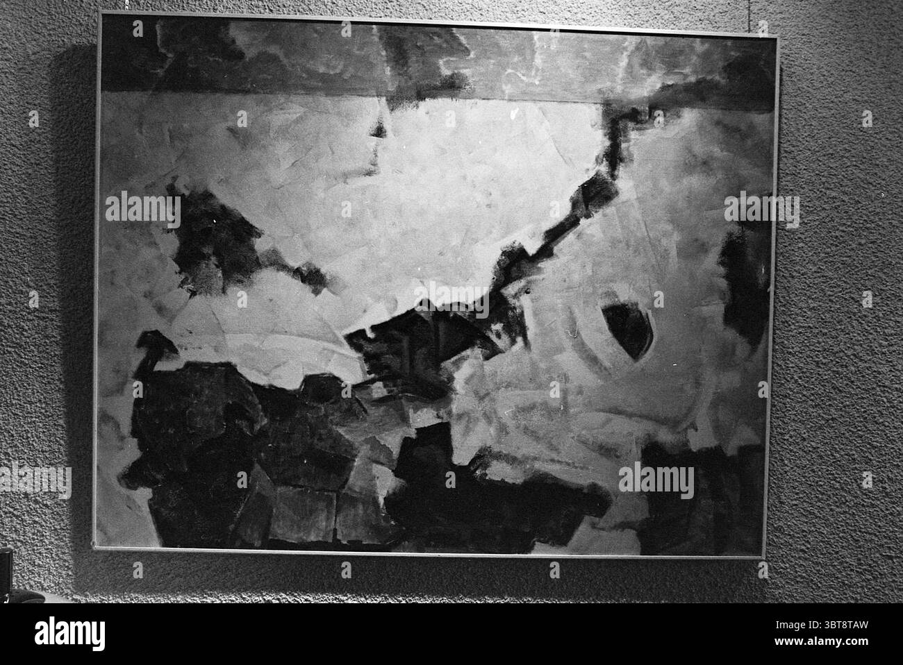 Mostra di Carpentier nella GEB North Holland Exhibition, Whizgle News, Dutch Desk, Paesi Bassi, 1950 - 2000 il 13-04-1977. Questi argomenti sono mostrati nell'immagine. La scena presenta una grande opera d'arte astratta, resa prevalentemente in tonalità di nero, bianco e grigio. La composizione appare dinamica, con tratti audaci e patch testurizzate che creano un senso di movimento lungo la tela. Le aree di carbone profondo contrastano con le macchie di bianco più leggere e quasi eteree, suggerendo profondità e dimensioni. Alcune sezioni sono fortemente stratificate, mentre altre sono più lisce, contribuendo a una i intrigante Foto Stock