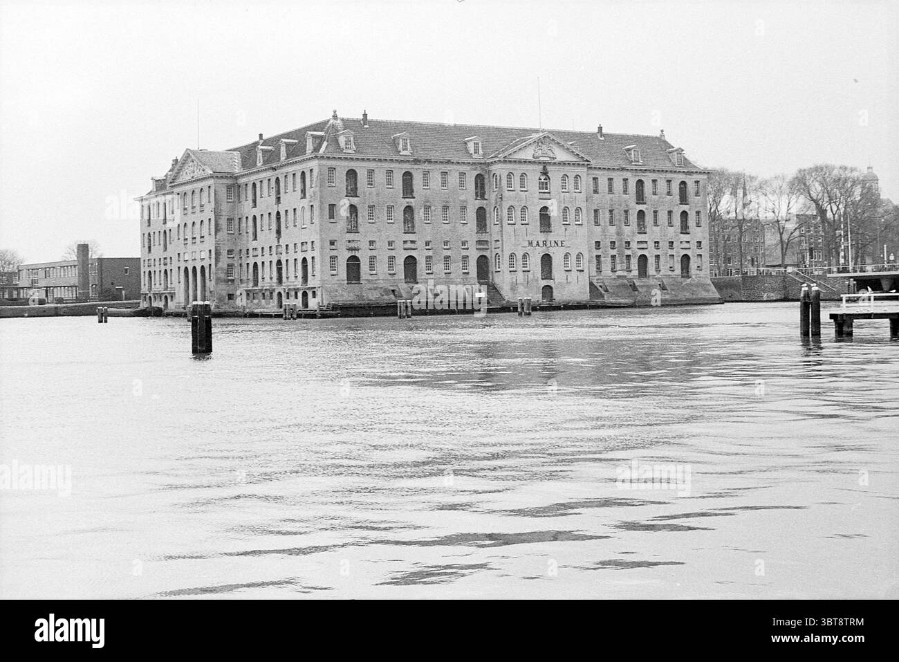 Maritime Museum Amsterdam Kattenburg 1 Nederland., Whizgle News, Dutch Desk, Paesi Bassi, 1950 - 2000. Questi argomenti sono mostrati nell'immagine. La scena presenta un imponente e grande edificio dallo stile architettonico storico, caratterizzato dalla sua struttura robusta e dalle numerose finestre. L'esterno dell'edificio e' reso in sfumature di grigio, suggerendo una superficie intemprata che ha resistito nel tempo, enfatizzando la sua eta' e il suo significato storico. Il tetto e' piatto con un leggero sbalzo e la facciata dell'edificio include finestre ad arco e una serie di disegni simmetrici che si aggiungono alla sua gran Foto Stock