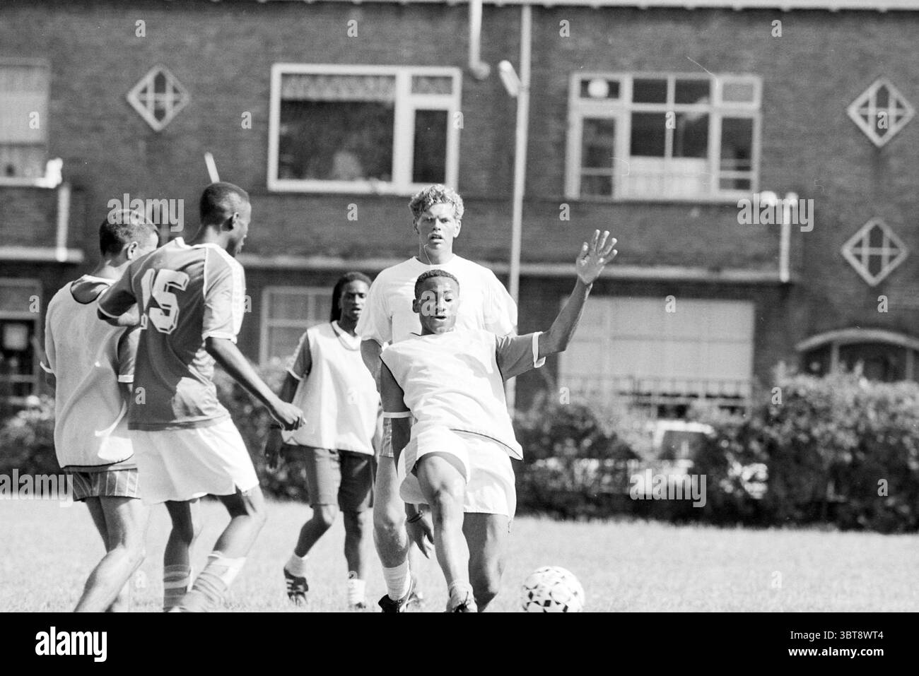 First Telstar training, Whizgle News, Dutch Desk, Paesi Bassi, 1950 - 2000 il 05-07-1992. Questi argomenti sono mostrati nell'immagine. In un ambiente vivace all'aperto, un gruppo di giovani uomini è impegnato in una partita di calcio vivace su un campo erboso. La scena è prevalentemente in tonalità di bianco e nero, conferendole un aspetto classico e senza tempo. I giocatori mostrano una gamma di dinamiche: Un atleta, vestito con una maglia bianca, ruota abilmente per fare un gioco. Ha un'espressione concentrata, con il corpo angolato verso il suolo mentre si prepara a colpire la palla. I suoi calzini sono tirati in alto, e i suoi pantaloncini sono scivolati Foto Stock