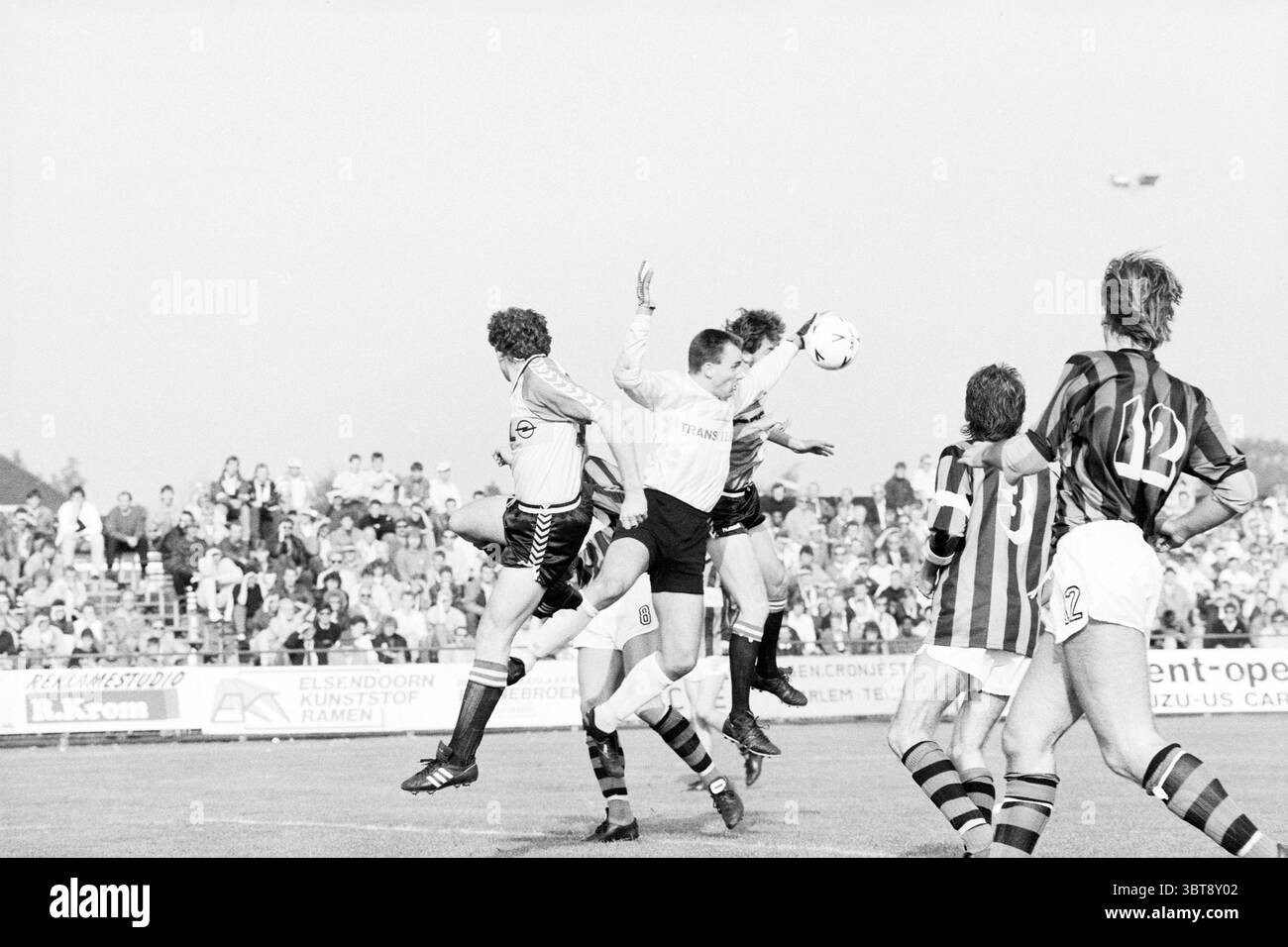RCH - Feyenoord Heemstede Paesi Bassi, Whizgle News, Dutch Desk, Paesi Bassi, 1950 - 2000 il 02-10-1988. Questi sono gli elementi dell'immagine. La scena cattura un momento dinamico in una partita sportiva, probabilmente una partita di calcio, che si svolge all'aperto. In primo piano, un gruppo di giocatori è impegnato in una vivace gara per il pallone. Gli atleti, vestiti con divise a contrasto, uno con strisce prevalentemente nere e l'altro bianco, mostrano intensità e determinazione fisica. Il giocatore in bianco salta in alto nell'aria, le braccia si estendono come se puntasse alla testa della palla, mentre altri no Foto Stock
