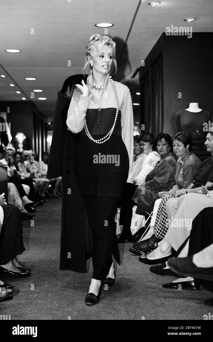 Sfilata di moda Lions Small size Haarlem Paesi Bassi, Whizgle News, Dutch Desk, Paesi Bassi, 1950 - 2000 il 17-09-1997. Questi argomenti vengono visualizzati nell'immagine. In un elegante ambiente boutique, un modello si muove con fiducia lungo una pista stretta sullo sfondo di spettatori elegantemente vestiti. Il modello è impreziosito da un look accattivante che combina un fondo nero aderente e un top a contrasto che sfoggia un mix di colori e texture. Il suo outfit è accentuato da un lungo cappotto drappeggiato che porta con sé una spalla, aggiungendo un tocco di raffinatezza. Il mod Foto Stock