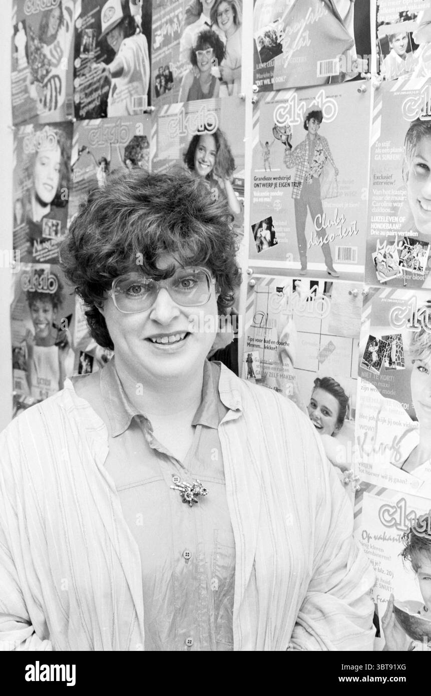 Annemarie Fassier VNU Kroniek VNU Association of Dutch Publishers, Whizgle News, Dutch Desk, Paesi Bassi, 1950 - 2000 il 04-11-1985. Questi sono gli argomenti nell'immagine. La scena mostra una donna in piedi di fronte a un muro adornata con diverse copertine di riviste con vari individui. La donna ha i capelli ricci e gli occhiali sportivi, indossando una camicia di colore chiaro che ha una calzata rilassata. Ha un sorriso dolce che trasmette un senso di calore e di disponibilità. Lo sfondo è vivace, pieno di copertine di riviste che mostrano un mix di celebrità e modelli, ciascuna delle quali presenta un tocco di vivacità Foto Stock