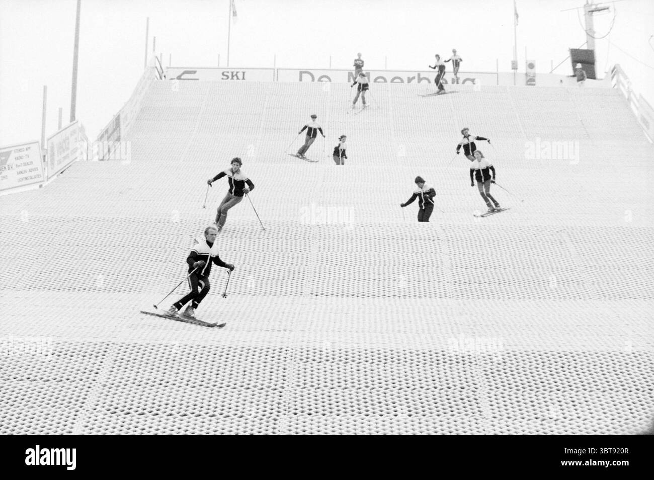 Apertura della pista da sci Hoofddorp apertura delle aperture per la messa in servizio degli sport da sci, Whizgle News, Dutch Desk, Paesi Bassi, 1950 - 2000 il 05-08-1978. Questi argomenti vengono visualizzati nell'immagine. La scena raffigura una pista da sci innevata piena di attività. Più sciatori stanno navigando con grazia lungo la pendenza, mostrando un mix di abilità. Gli sciatori sono vestiti con una varietà di attrezzature invernali, prevalentemente tonalità scure con alcuni tocchi di colore, che si distinguono sullo sfondo bianco della neve. La pendenza è strutturata con una superficie strutturata, simile a quella di una griglia, che probabilmente indica la neve artificiale Foto Stock
