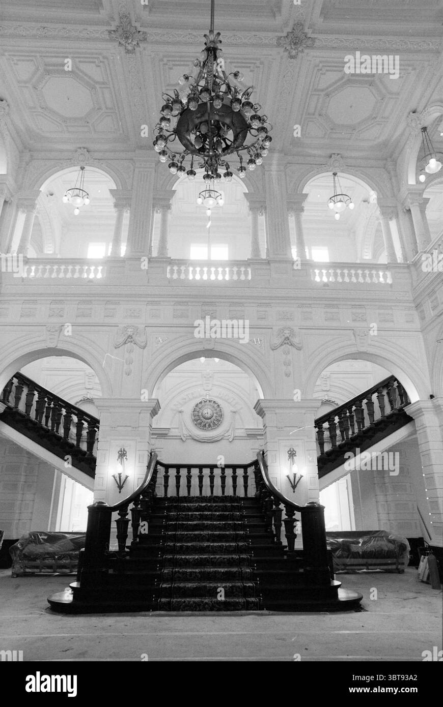 Sala interna dell'Amstelhotel ad Amsterdam Amsterdam, Paesi Bassi, Whizgle News, Dutch Desk, Paesi Bassi, 1950 - 2000 al 26-08-1992. Questi sono gli argomenti nell'immagine. La scena presenta un interno ampio ed elegante, dominato da una grande scalinata che sale con grazia in modo simmetrico. La scala presenta gradini di legno scuro e lucido, che contrastano splendidamente con le pareti di colore chiaro adornate da intricate modanature ed elementi decorativi. Sopra, uno splendido lampadario appeso maestosamente ad un alto soffitto decorato. L'illuminazione è morbida ma luminosa, Foto Stock