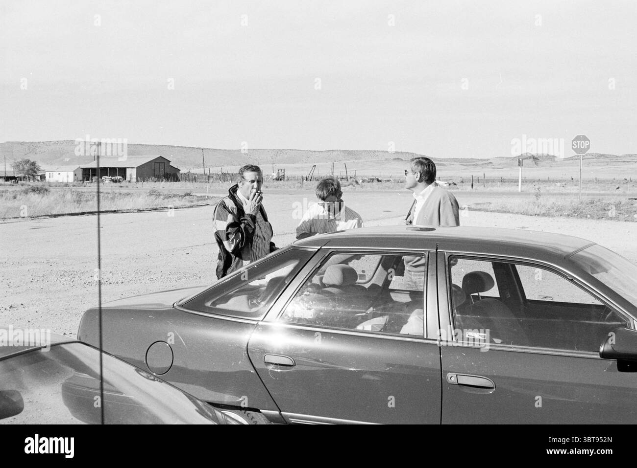 Kinheim Gentlemen in tour negli Stati Uniti, Whizgle News, Dutch Desk, Paesi Bassi, 1950 - 2000 il 09-11-1990. Questi argomenti sono mostrati nell'immagine. In questa scena, tre persone sono impegnate in una conversazione accanto a un'auto parcheggiata con un esterno lucido e scuro. Una persona, vestita con una giacca a motivi geometrici, sta con la schiena rivolta verso la fotocamera, gestendo con le mani mentre un'altra persona, con una giacca leggera, le guarda con un look concentrato. Il terzo individuo, posizionato leggermente dietro il gruppo, ha un'espressione neutrale, contribuendo alla conversazione. L'impostazione sembra essere un Foto Stock