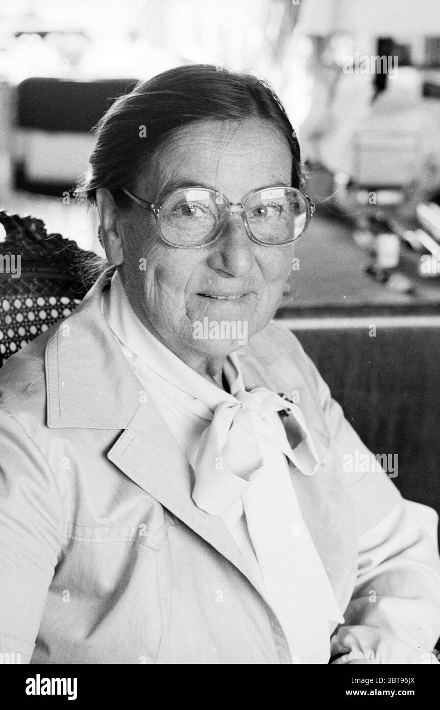 Ritratto Signora Reeser insegnante di musica ritratti persone canto e musica, Whizgle News, Dutch Desk, Paesi Bassi, 1950 - 2000 il 20-09-1979. L'immagine include questi argomenti. La scena presenta una donna anziana seduta comodamente in un interno ben arredato. Ha un'espressione delicata, caratterizzata da morbide rughe che raccontano storie del tempo. I suoi grandi occhiali rotondi riflettono la luce ambientale, sottolineando delicatamente il suo sguardo attento. La donna indossa un blazer di colore chiaro su una blusa bianca, completata da una semplice ed elegante cravatta che aggiunge raffinatezza. I suoi capelli sono ben modellati, Foto Stock