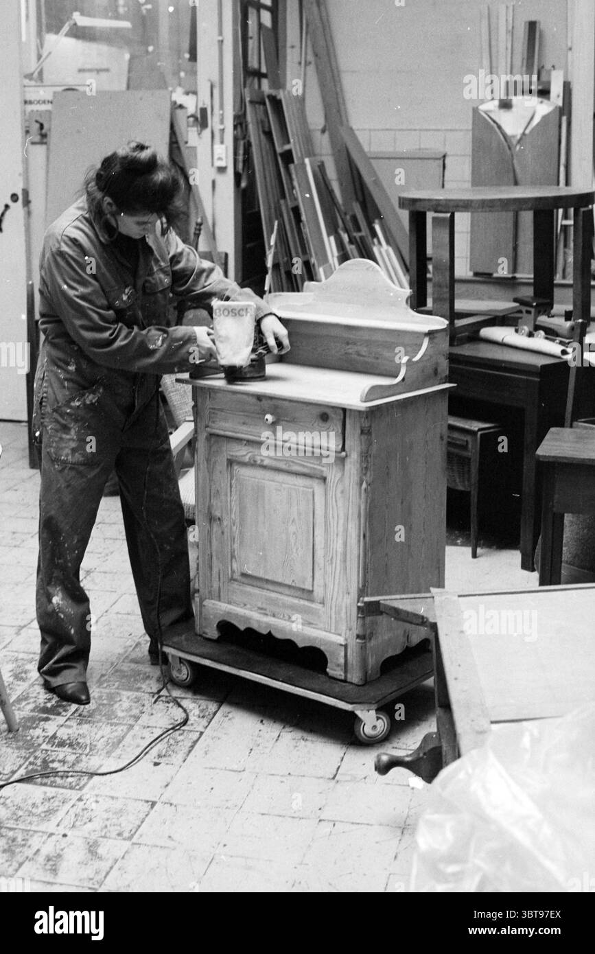 De Schalm - progetto Haarlem, Whizgle News, Dutch Desk, Paesi Bassi, 1950 - 2000 il 13-10-1993. L'immagine mostra questi argomenti. In una spaziosa officina piena di vari mobili, una persona si concentra sulla rifinitura di un armadio in legno. L'armadietto, realizzato in legno chiaro, ha un design semplice con un piccolo cassetto nella parte superiore e una porta sotto ornata da delicati pannelli. La sua venatura naturale è visibile, a indicare la maestria artigianale del pezzo. L'individuo che lavora all'armadietto è vestito con tute da lavoro, suggerendo un approccio pratico al restauro di mobili. I loro capelli sono tirati bac Foto Stock