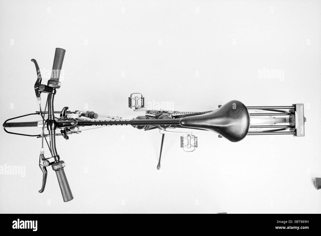 Bicicletta in connessione con due ruote Rai, Whizgle News, Dutch Desk, Paesi Bassi, 1950 - 2000 il 11-02-1992. L'immagine mostra questi argomenti. La scena mostra una bicicletta vista dall'alto, presentando una composizione simmetrica e strutturata. Il telaio della moto è realizzato con linee eleganti, evidenziate da una tavolozza monocromatica che enfatizza le sfumature contrastanti del bianco e nero. Il manubrio si estende verso l'esterno, con impugnature nere che ne migliorano l'aspetto tattile. Le leve del freno, elegantemente arcuate, sono posizionate vicino alle impugnature, aggiungendo una funzionalità complessiva del design. Belo Foto Stock