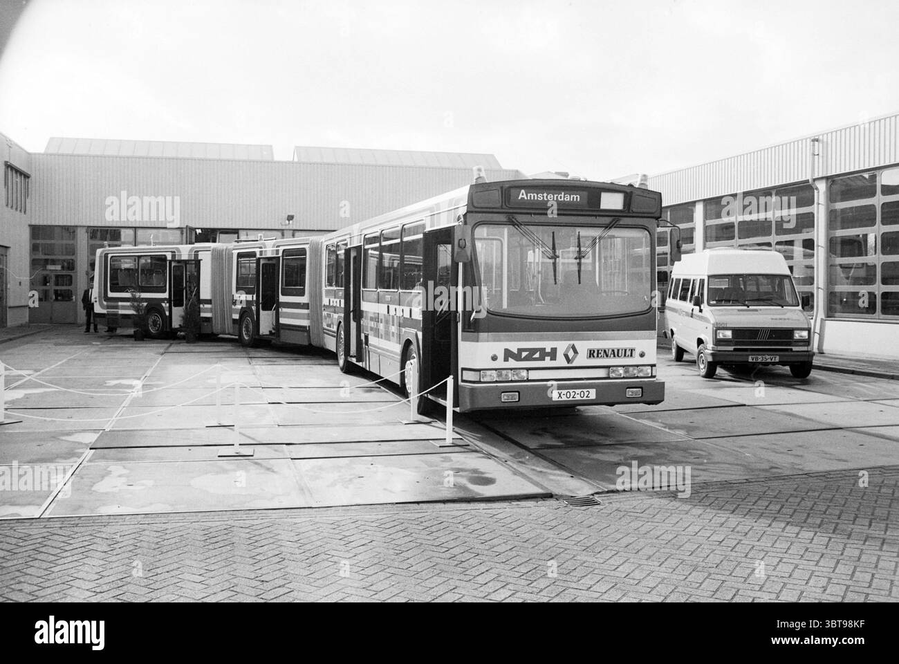 Presentazione NZH Mega-bus Purmerend Noord Zuid Hollandse Vervoersmaatschappij N.V. NZ Purmerend, Whizgle News, Dutch Desk, Paesi Bassi, 1950 - 2000 il 02-11-1988. Questi sono gli elementi dell'immagine. La scena cattura uno spazioso deposito di trasporto urbano dominato da diversi veicoli, principalmente autobus. In primo piano spicca un autobus di spicco, contrassegnato con il nome "Renault" e identificato come parte del sistema di trasporto pubblico. La parte anteriore presenta un parabrezza di grandi dimensioni e bordi arrotondati, dipinti in una tavolozza di grigi e bianchi tenui. Il logo distinto aggiunge un tocco di contrasto Foto Stock