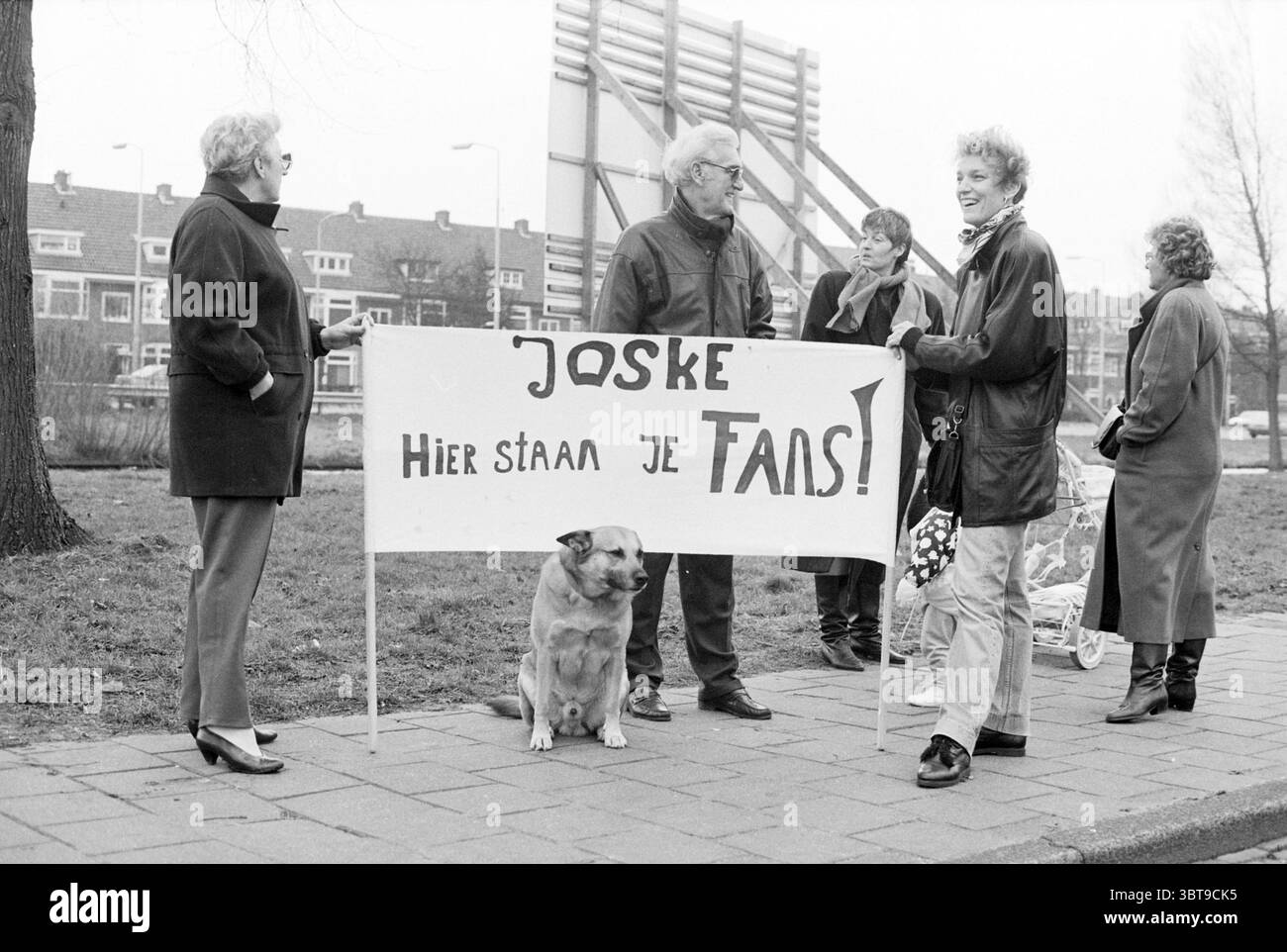 Triathlon invernale H'lem Haarlem Paesi Bassi, Whizgle News, Dutch Desk, Paesi Bassi, 1950 - 2000 il 21-02-1992. Questi argomenti vengono visualizzati nell'immagine. La scena è ambientata in una giornata grigia, offrendoti una qualità morbida e silenziosa alla luce. Un gruppo di diverse persone è riunito su un marciapiede, incorniciato su uno sfondo di edifici urbani caratterizzati da un mix di mattoni e architettura moderna. L'atmosfera è attiva ma informale, suggerendo un senso di coinvolgimento della comunità. In primo piano, una donna sta reggendo un grande cartello fatto a mano che sembra trasmettere un messaggio di sostegno, probabilmente tifo Foto Stock