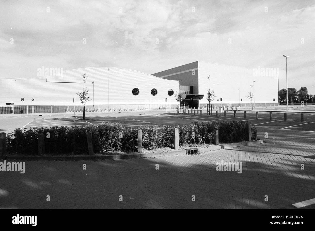 Esterno Extran Sports hall Haarlem Paesi Bassi, Whizgle News, Dutch Desk, Paesi Bassi, 1950 - 2000 il 23-06-1994. Questi sono gli argomenti nell'immagine. La scena presenta un grande e moderno edificio caratterizzato dalla sua architettura elegante e curva e dall'esterno distintivo. La facciata è principalmente una sfumatura di grigio o bianco, con una consistenza liscia che riflette delicatamente la luce ambientale. All'avanguardia, ci sono finestre circolari incorporate nel muro, che aggiungono un'interessante caratteristica visiva che contrasta con il design altrimenti lineare. Intorno all'edificio c'è un ampio parcheggio, m Foto Stock